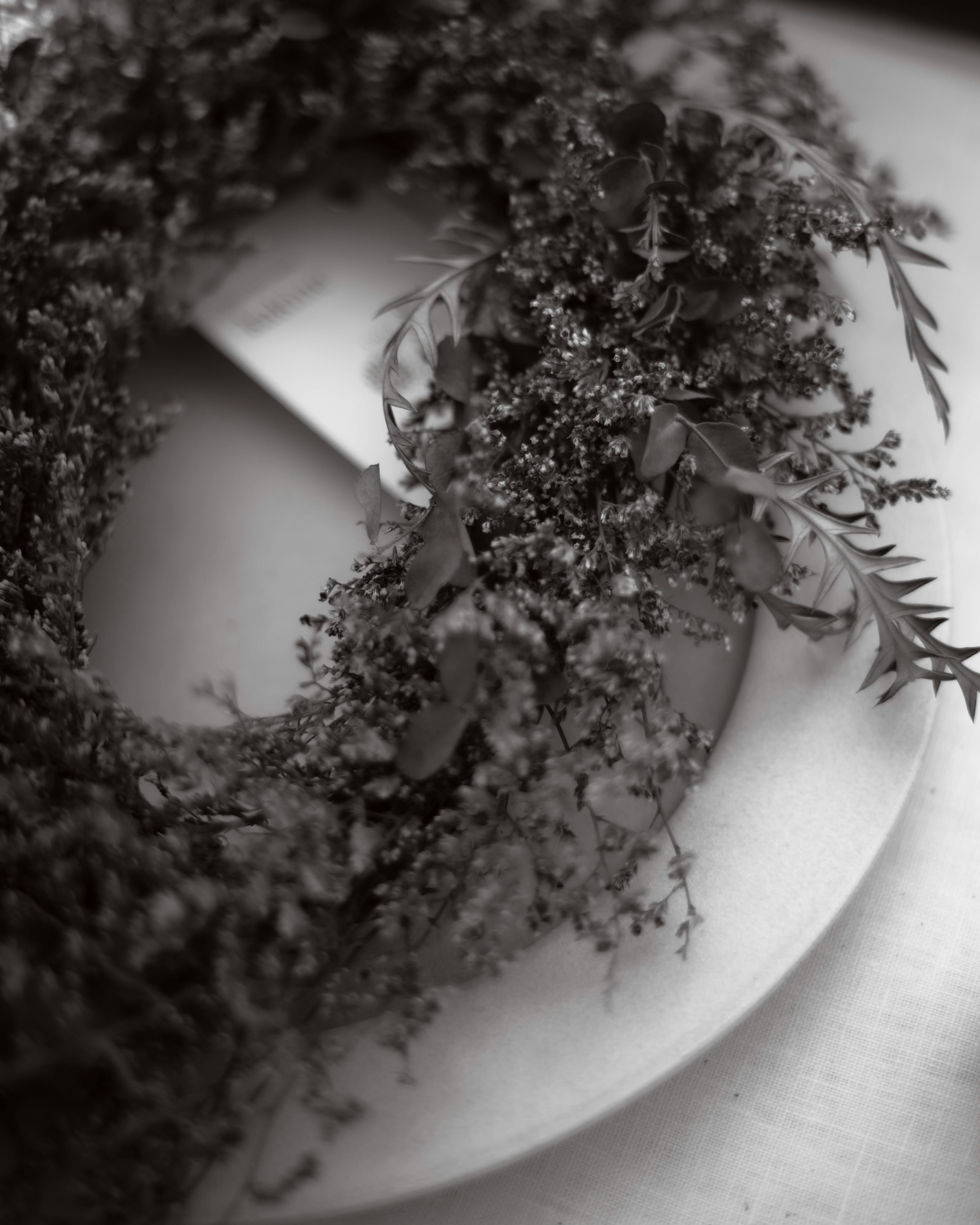 A green wreath placed on a white plate in black and white