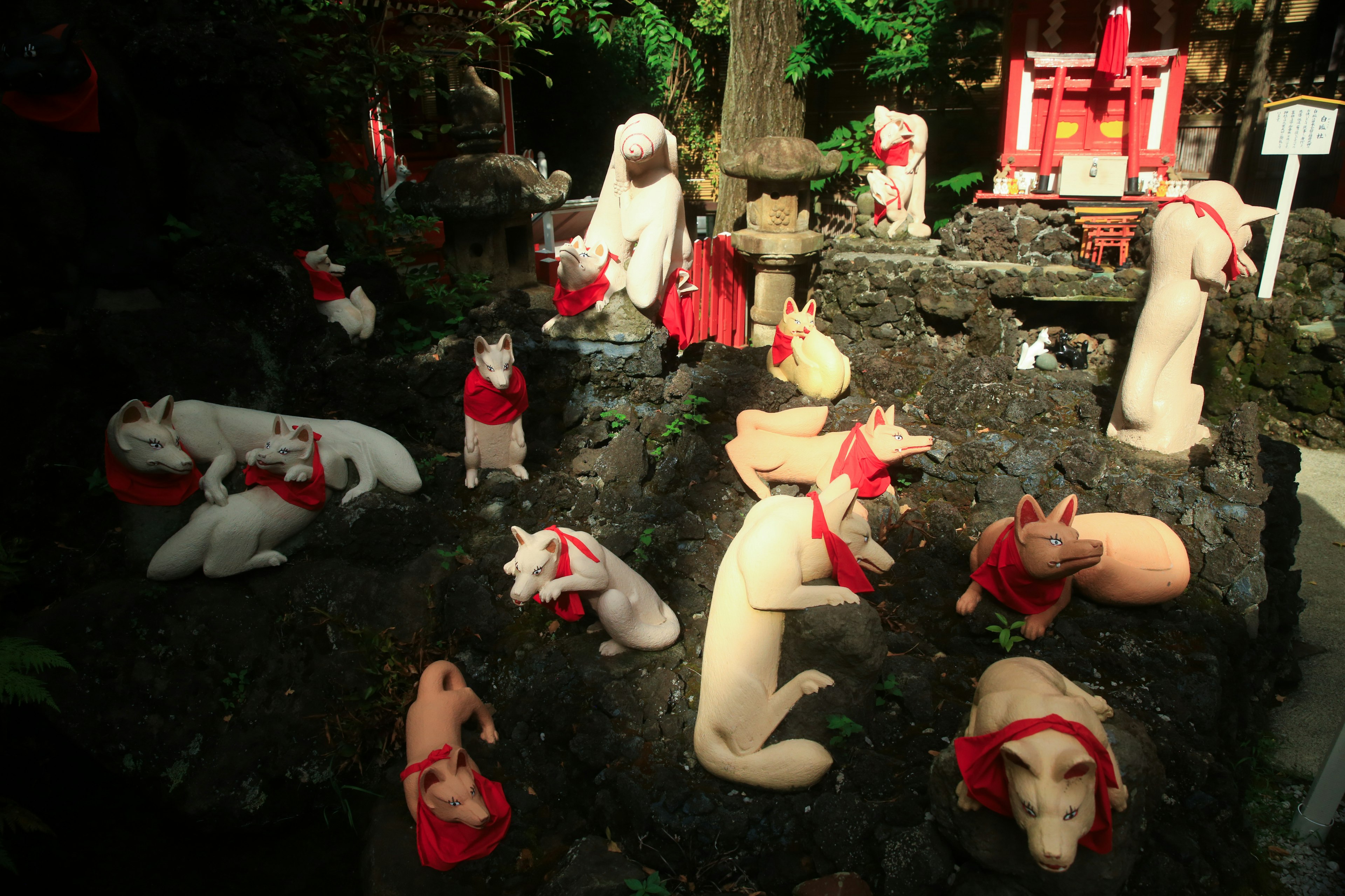 赤いマントを着た多くの犬の像がある神社の風景