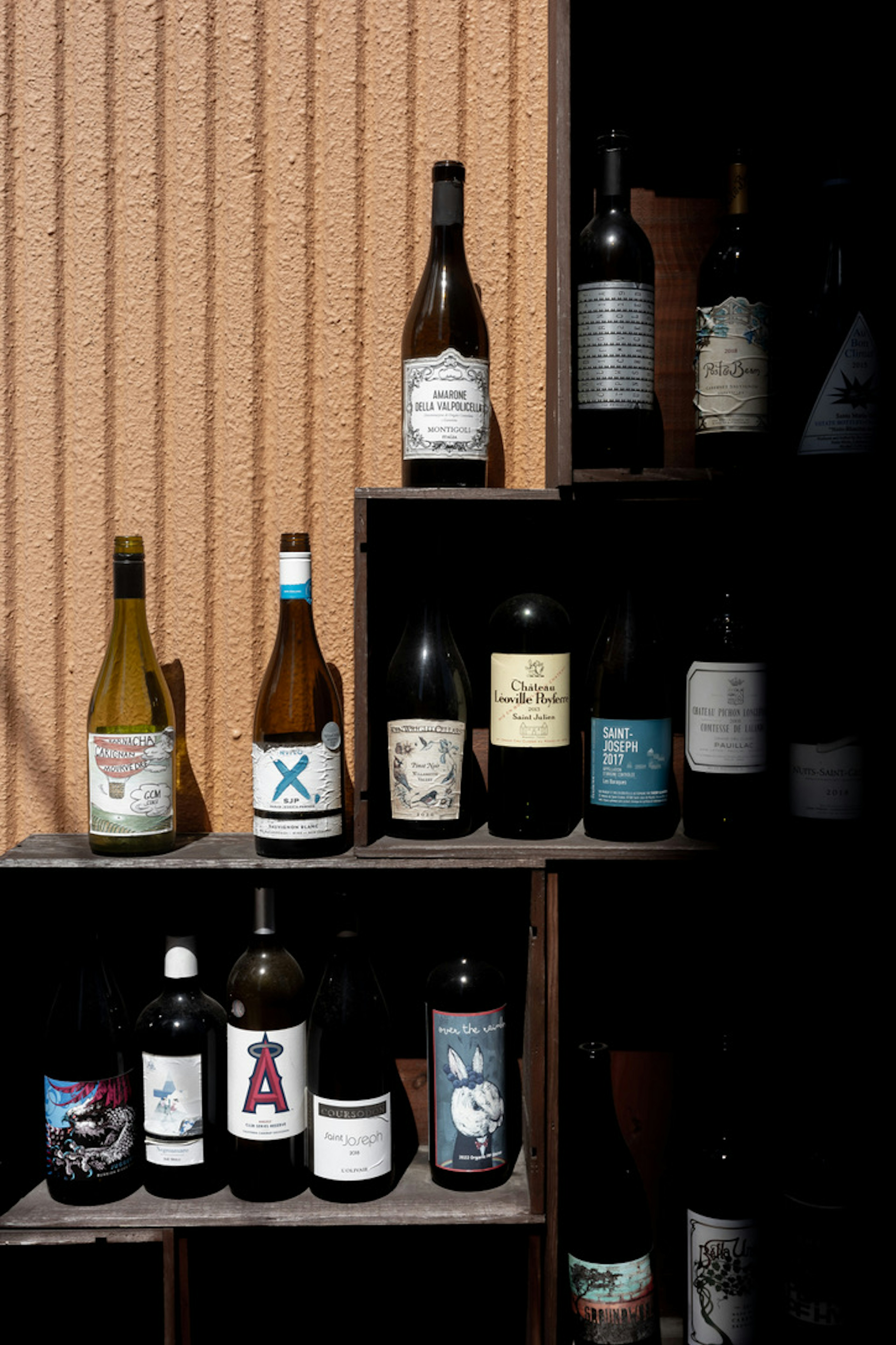 Image of a shelf displaying wine bottles with various labels and colors