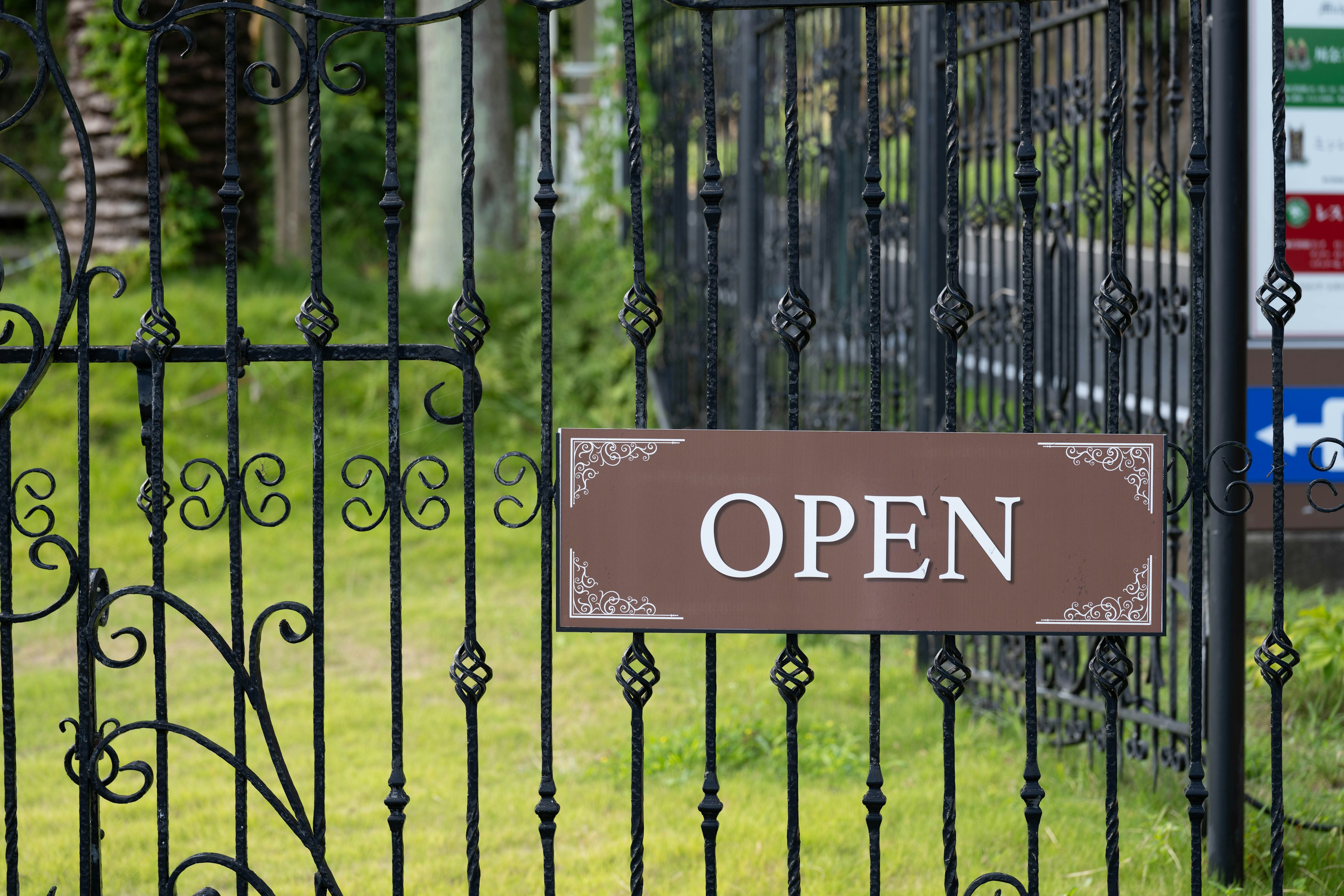 Iron gate with an open sign and green grass