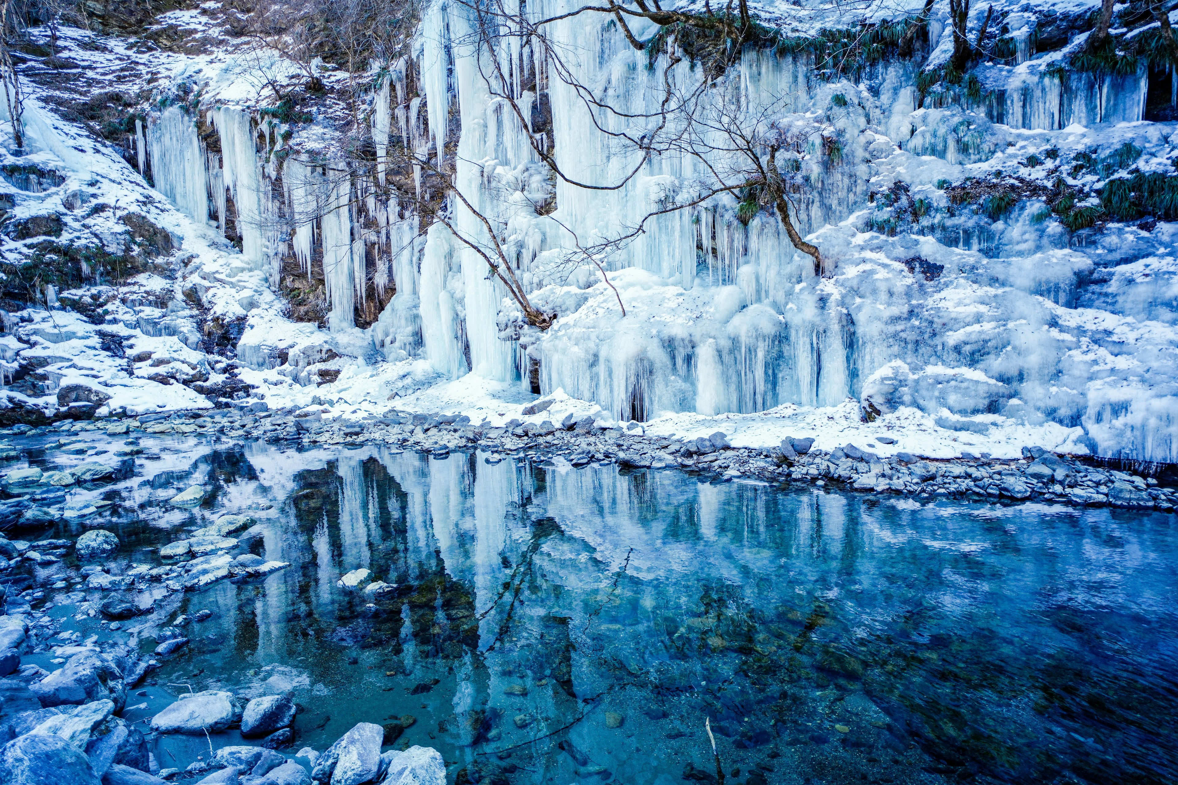 Paesaggio invernale con cascate di ghiaccio e superficie d'acqua blu riflettente