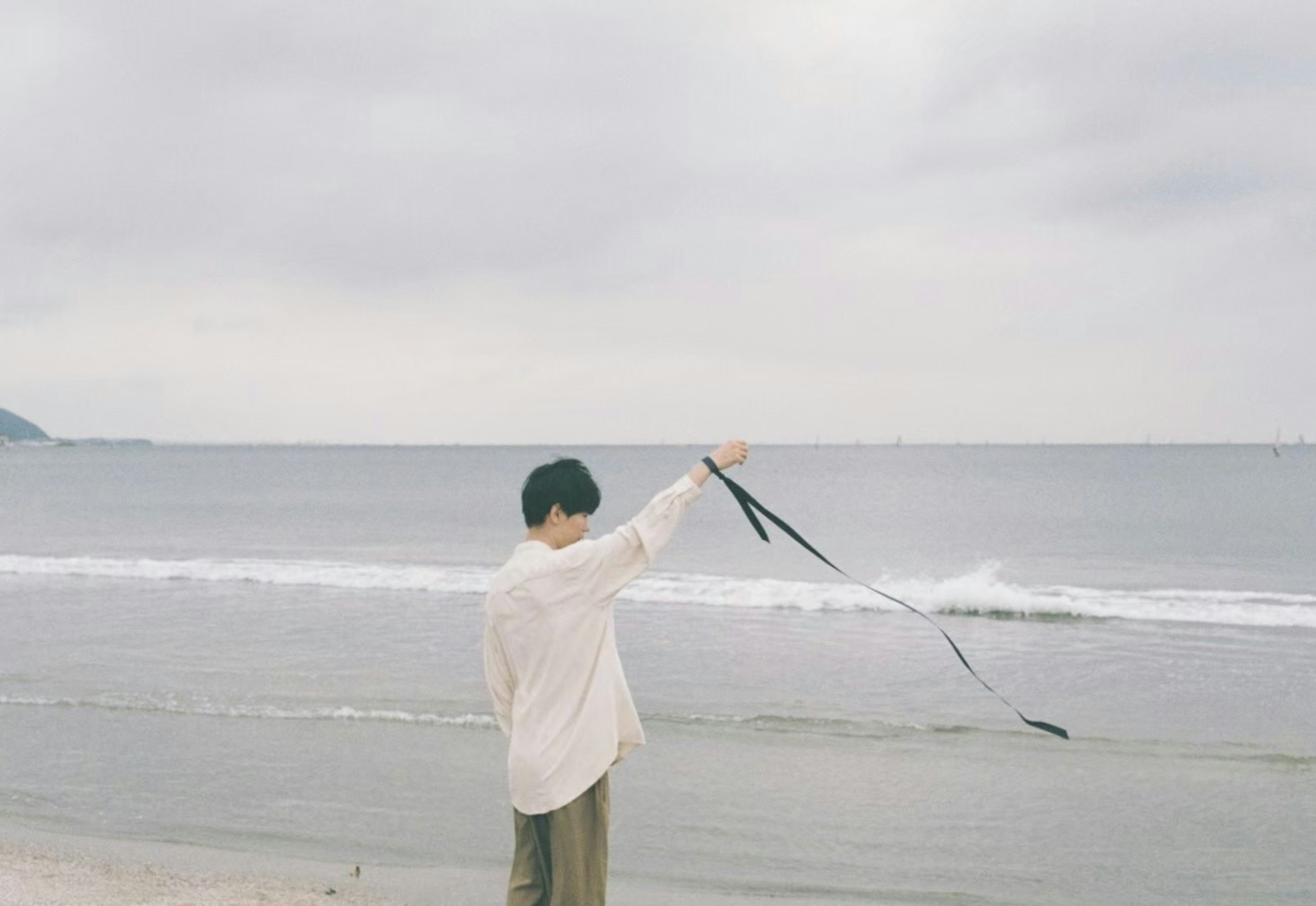 海辺でリボンを持っている男性の後ろ姿