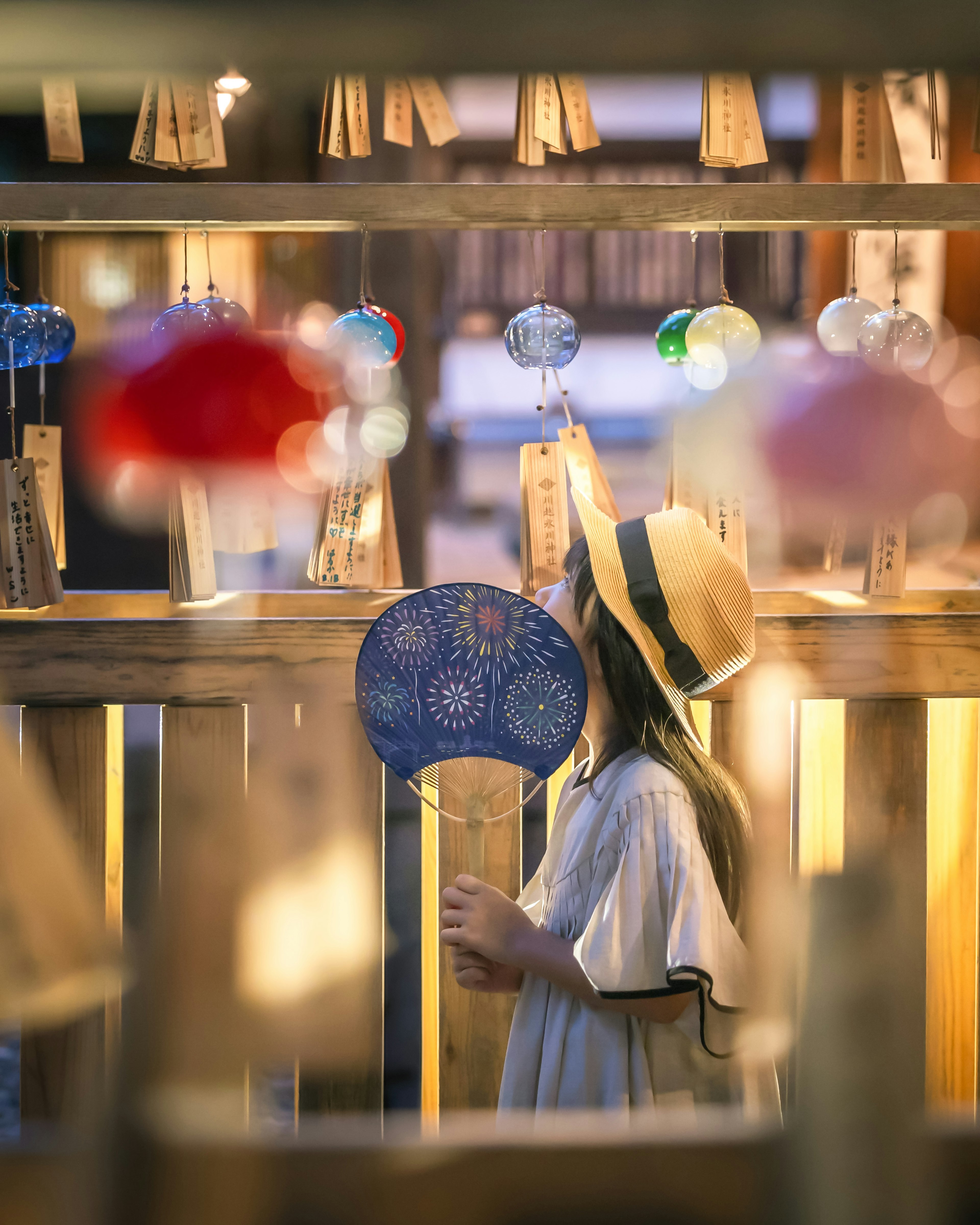 夏祭りの屋台で風鈴を見上げる少女の姿