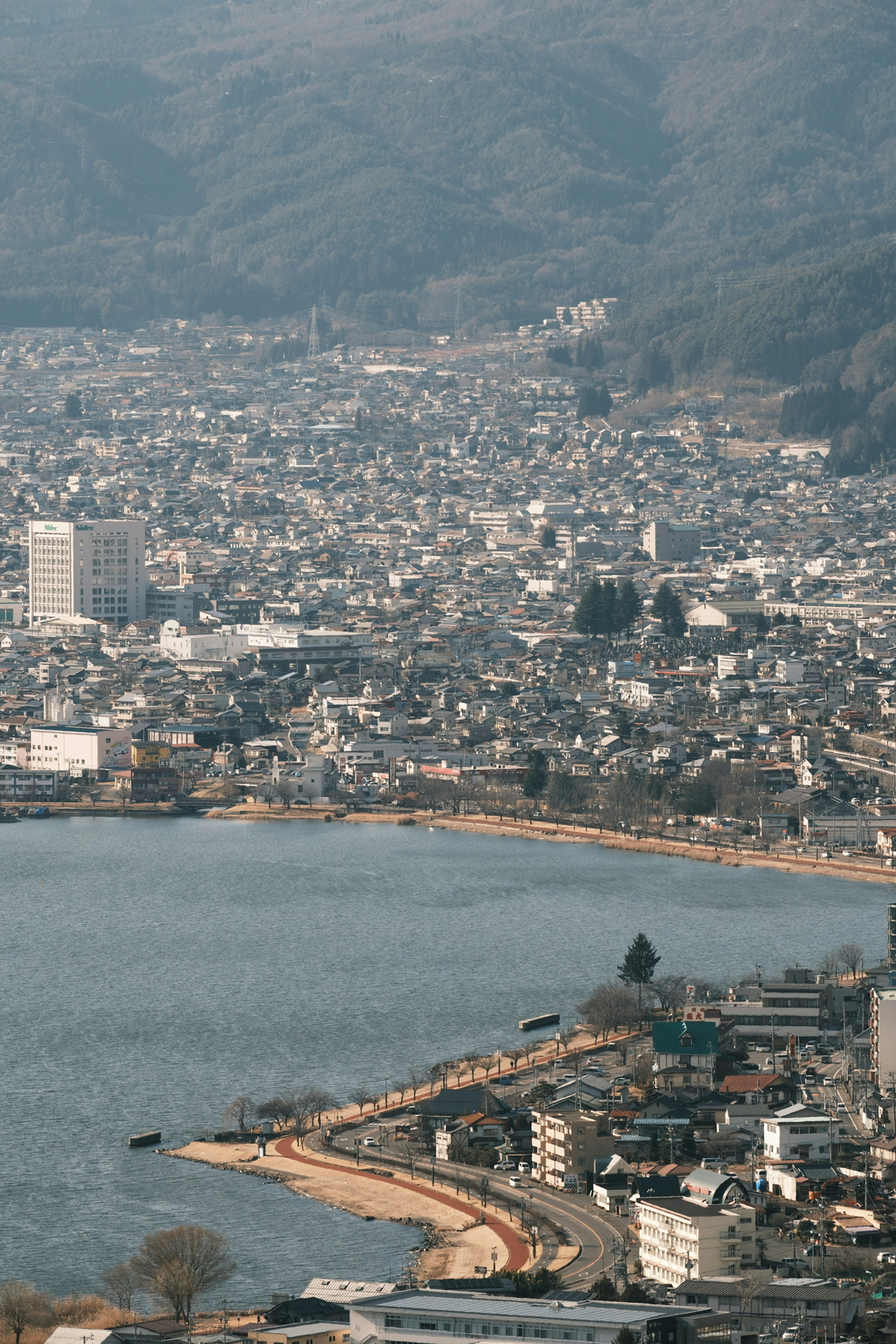 Aerial view of a city by the lake surrounded by mountains