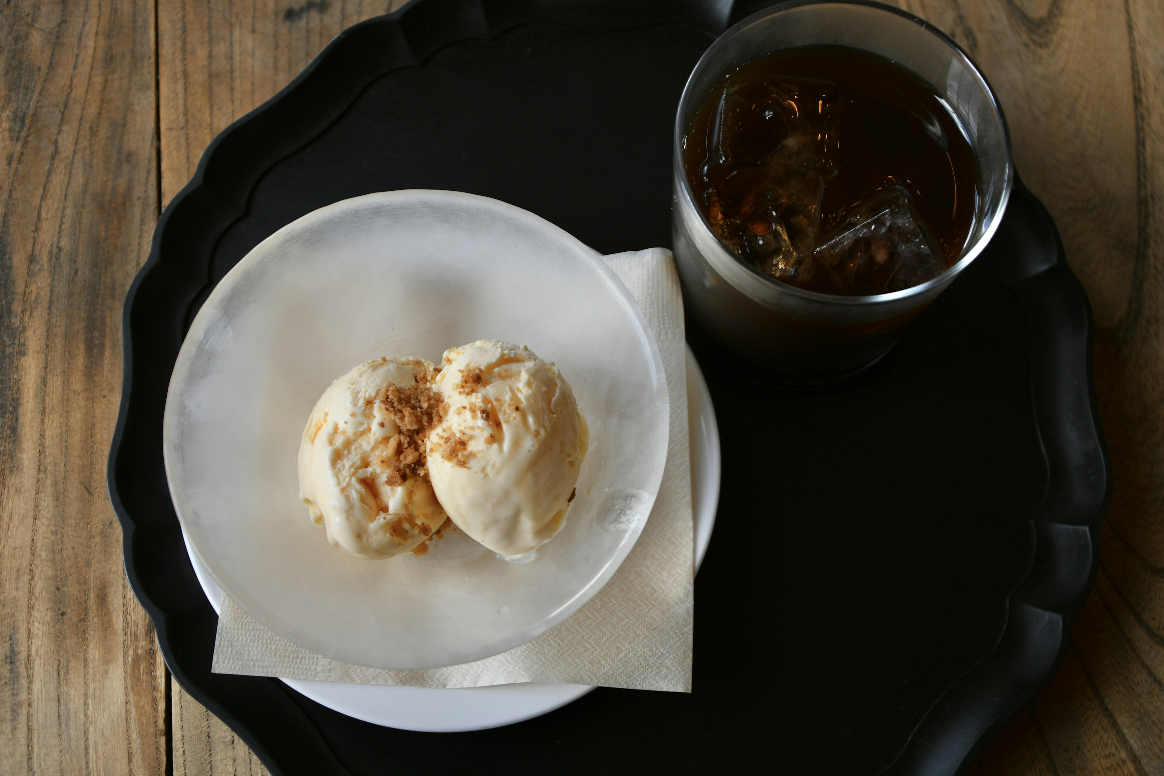 Ice cream on a white plate with a glass of drink