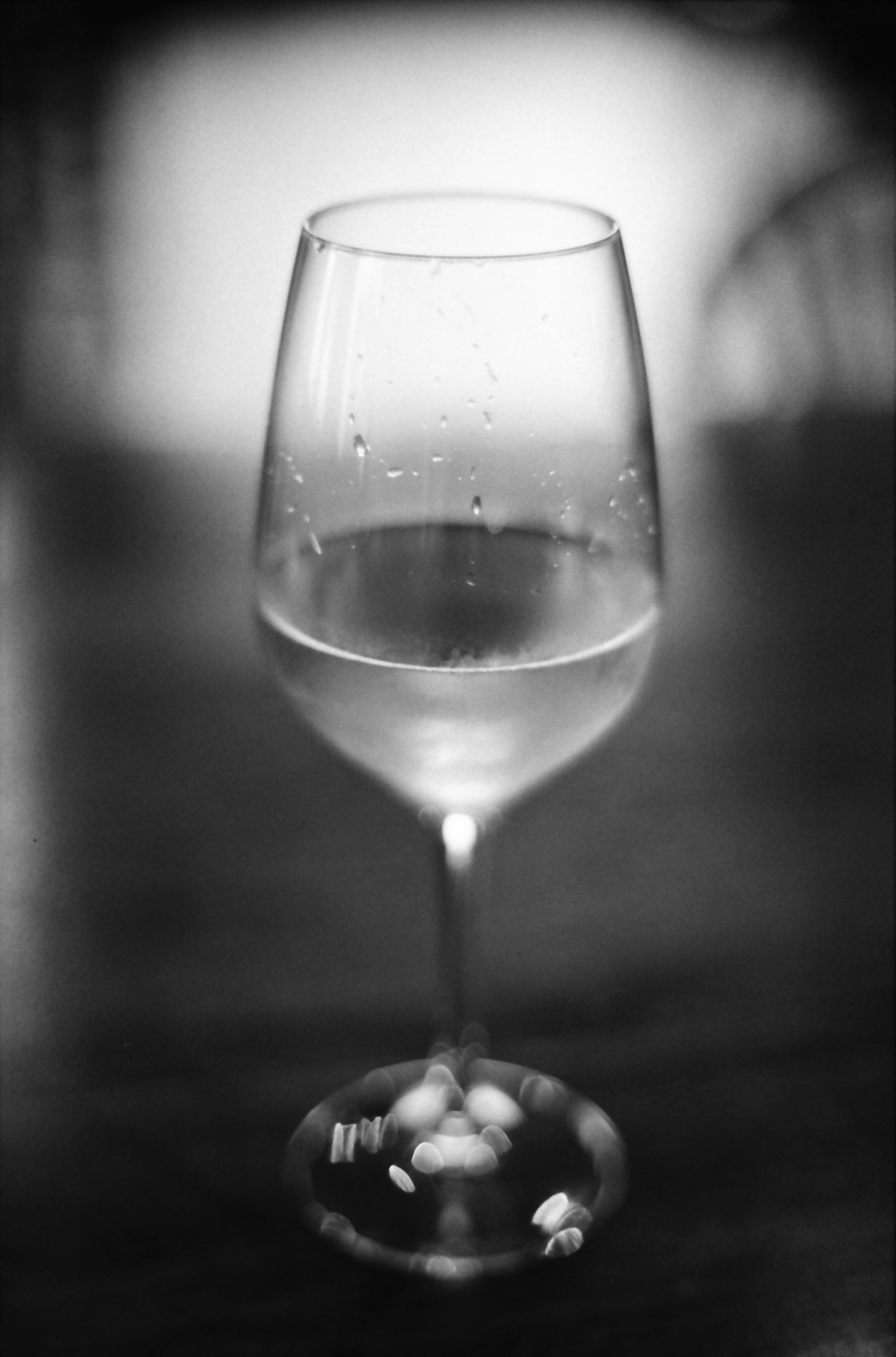 Una copa de vino transparente con gotas de agua sobre una mesa