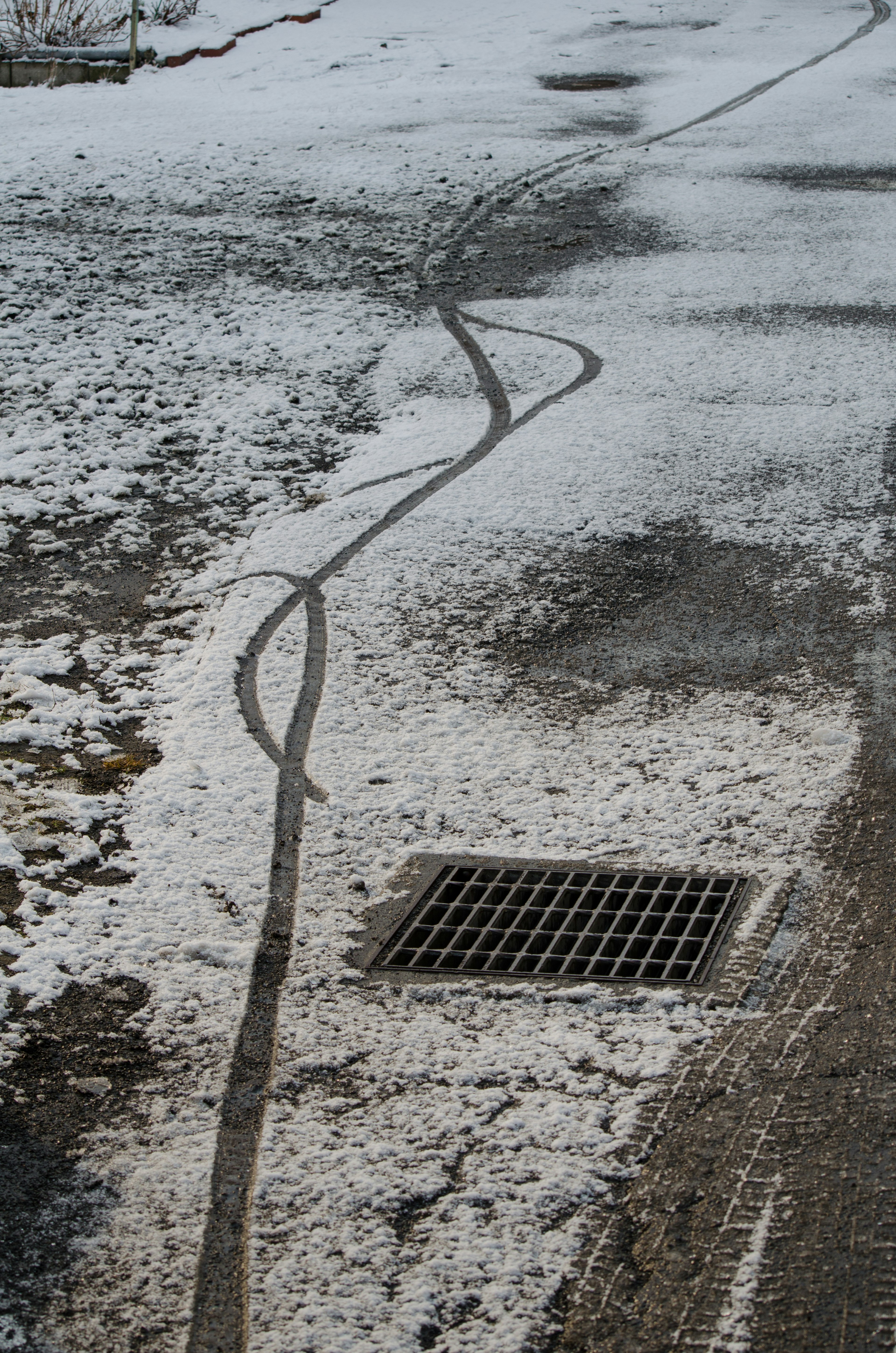 Smooth tire tracks on a snowy road with a drain