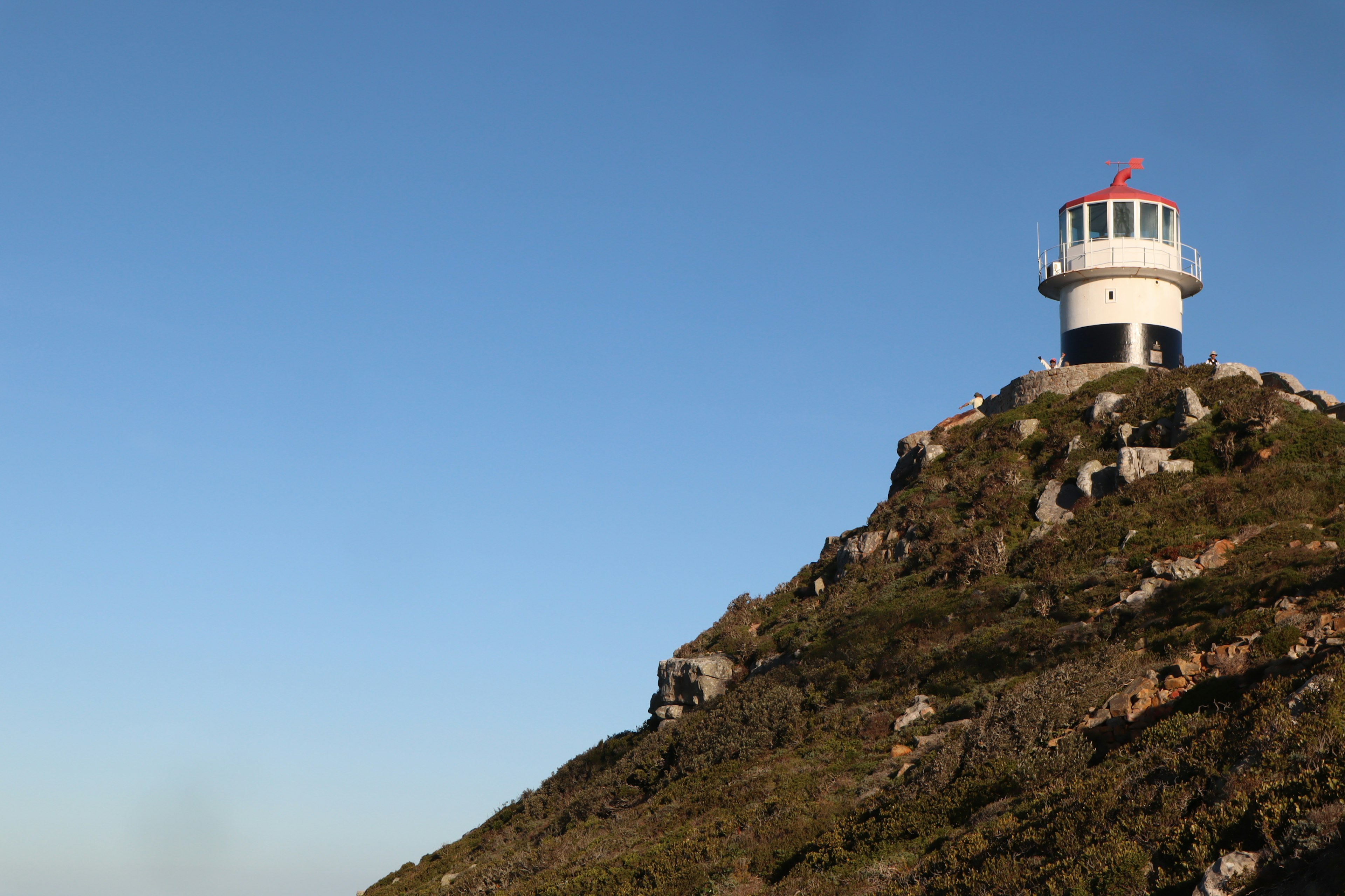 Phare sur une colline avec ciel bleu clair