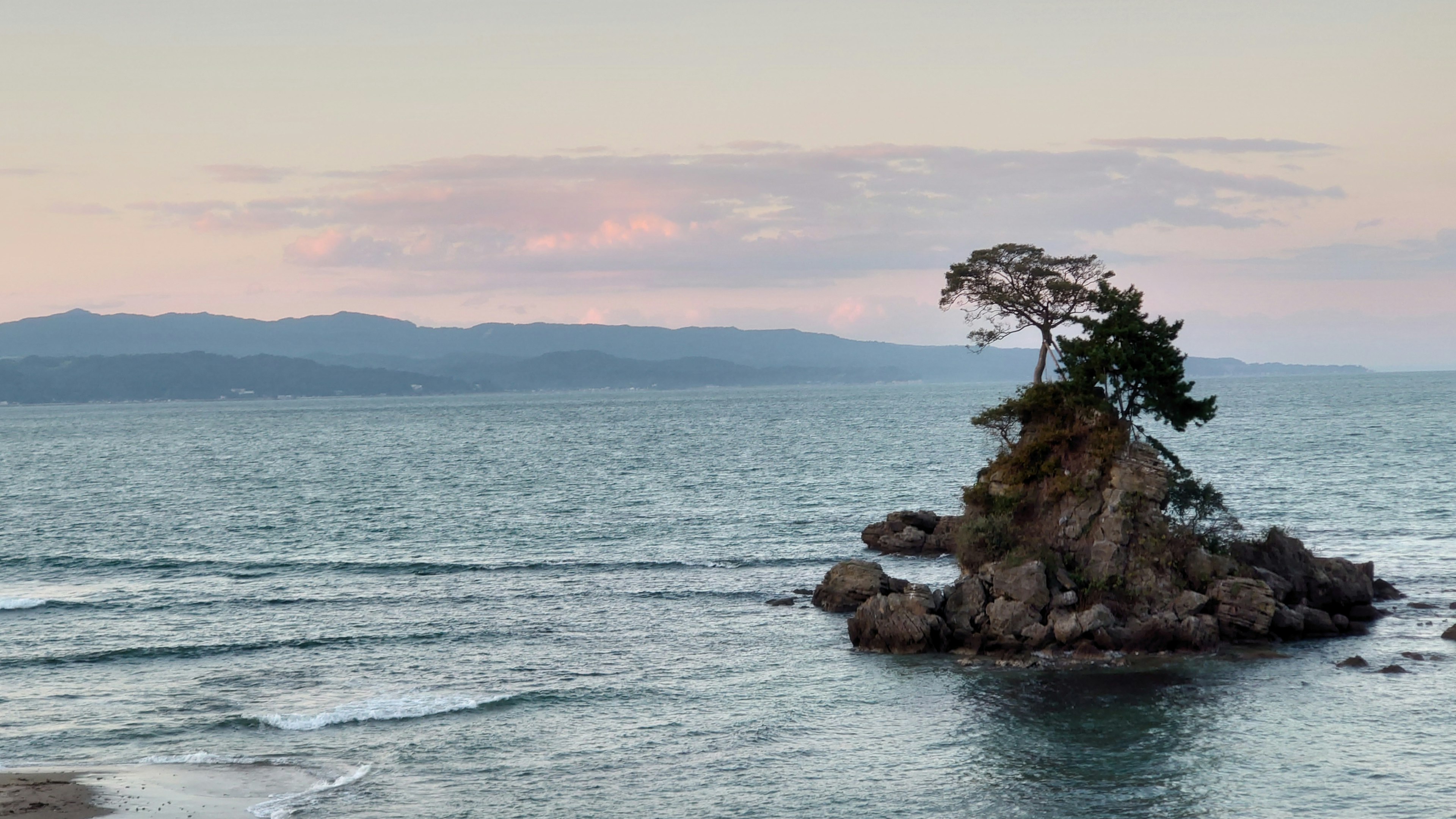 Une petite île avec des arbres située dans la mer au coucher du soleil