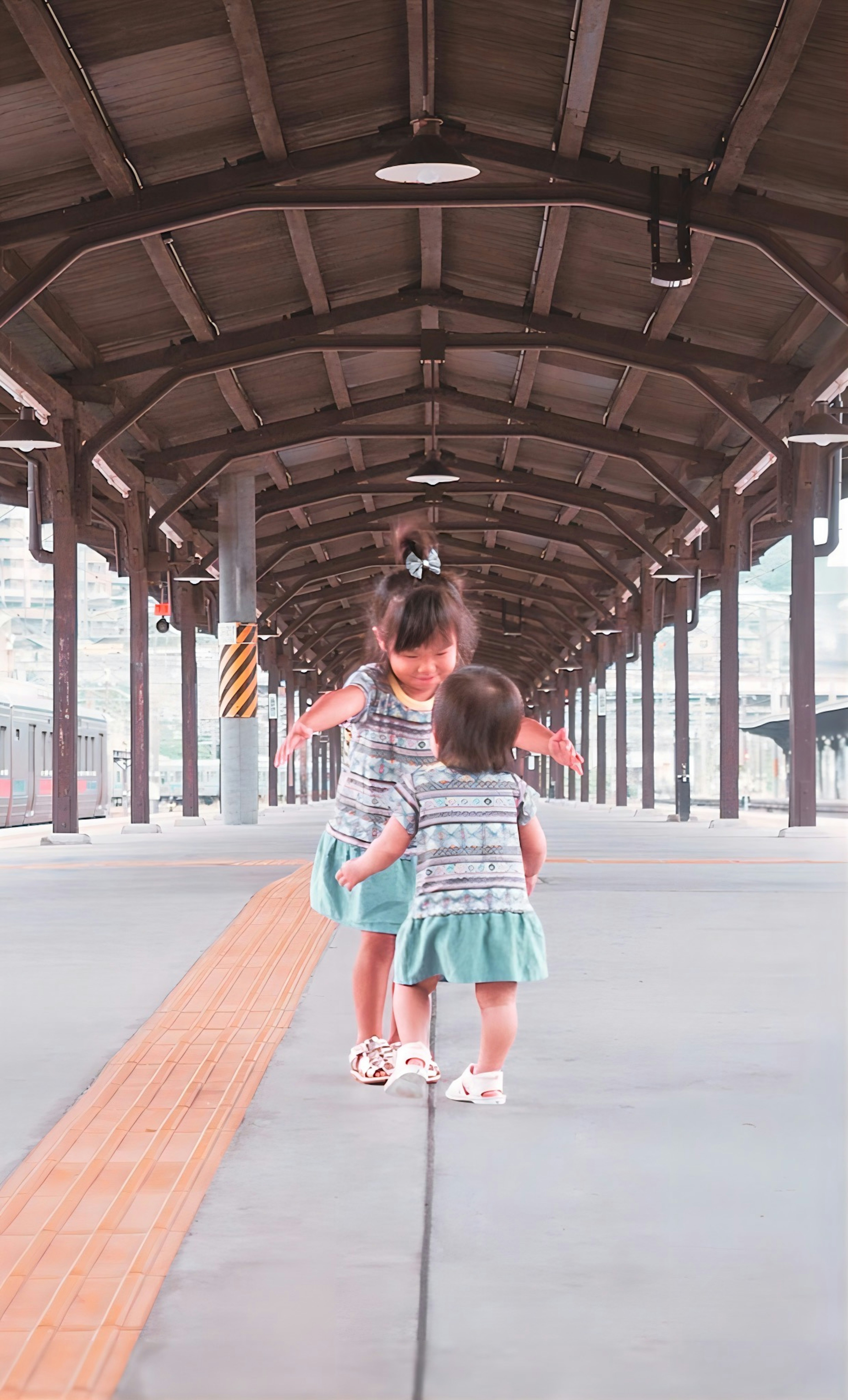 Two girls playing on a train platform