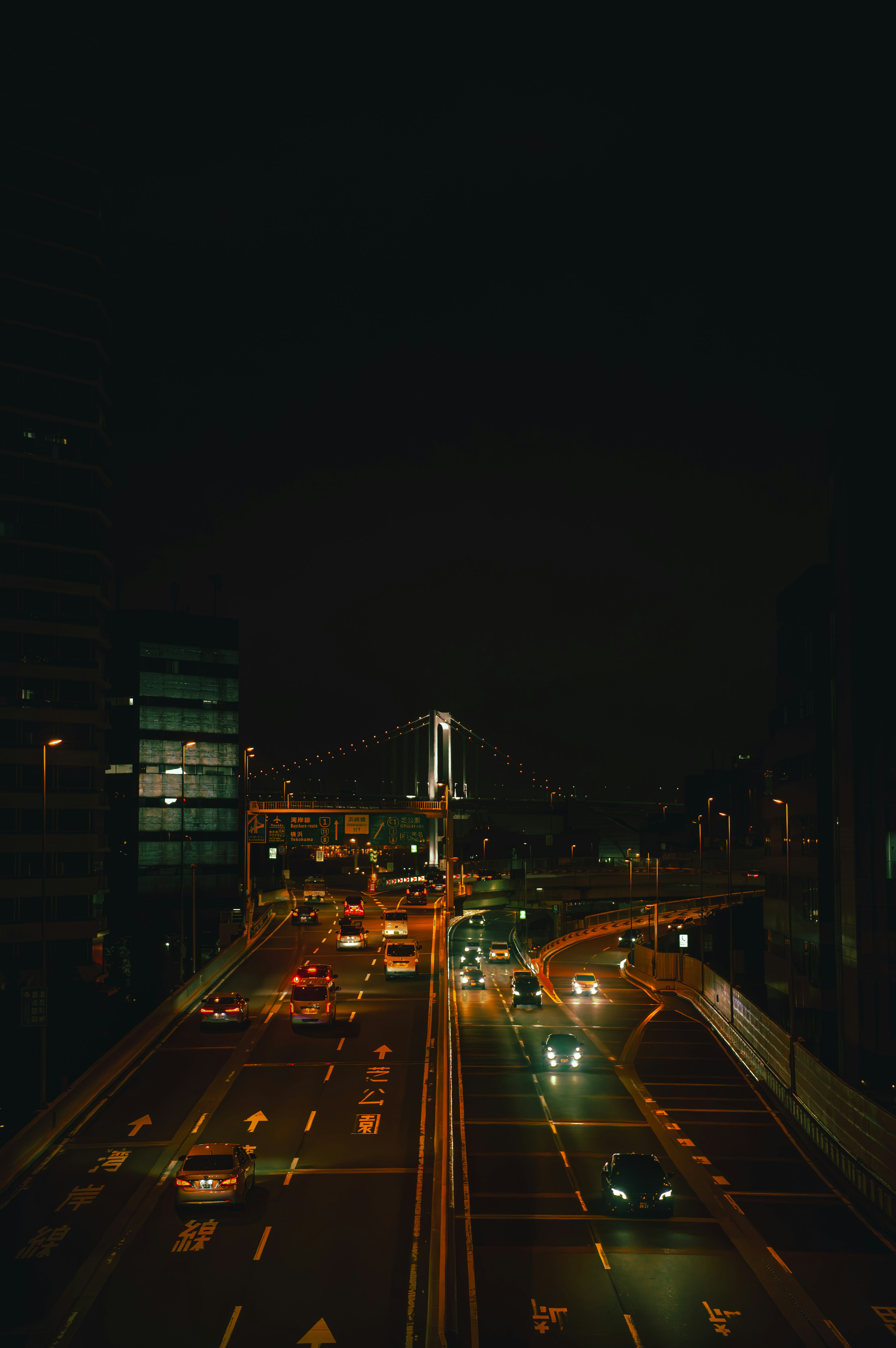 Paisaje urbano nocturno con un puente iluminado y tráfico fluido