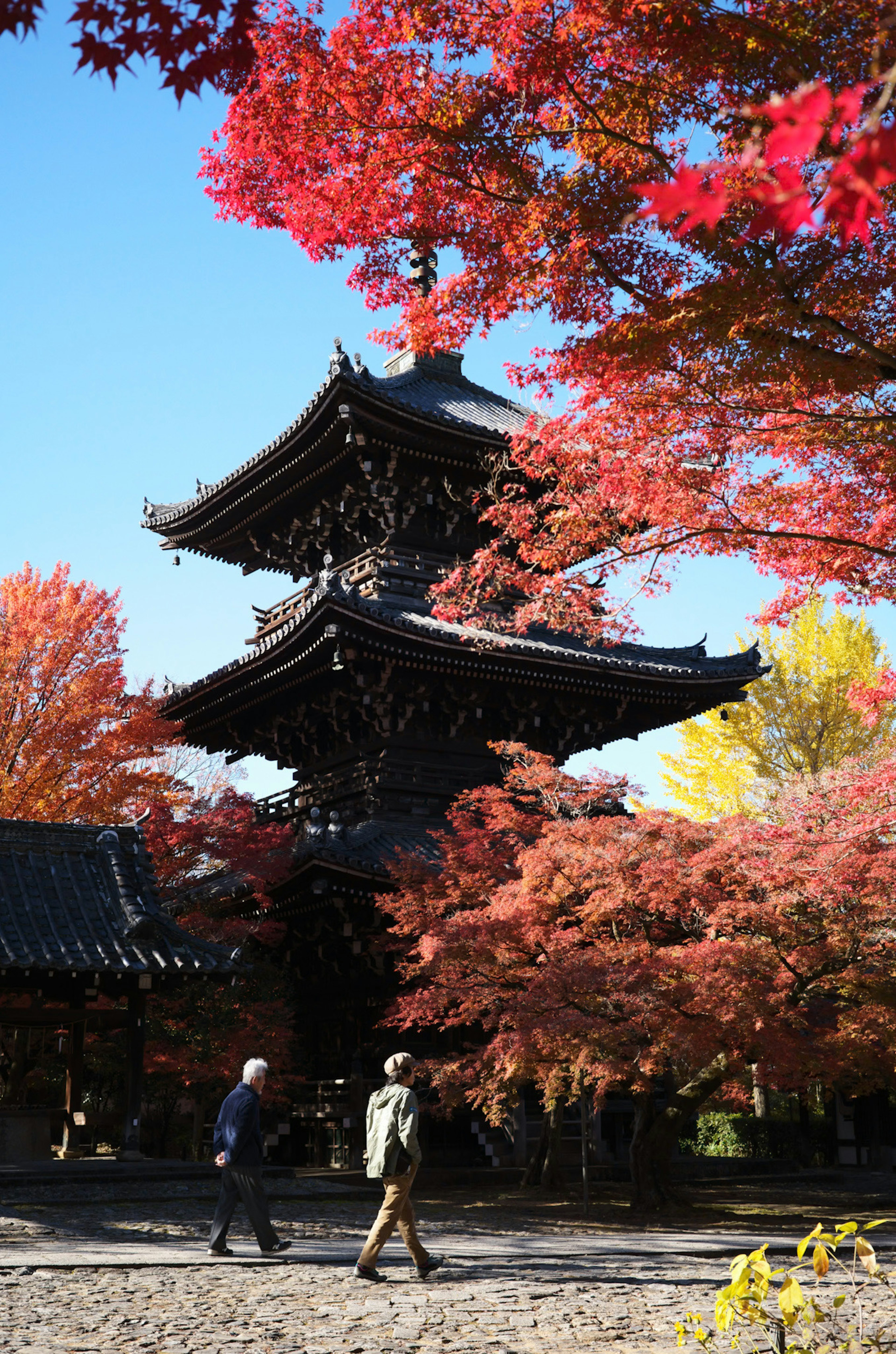 Pagoda giapponese tradizionale circondata da foglie autunnali con persone che passeggiano