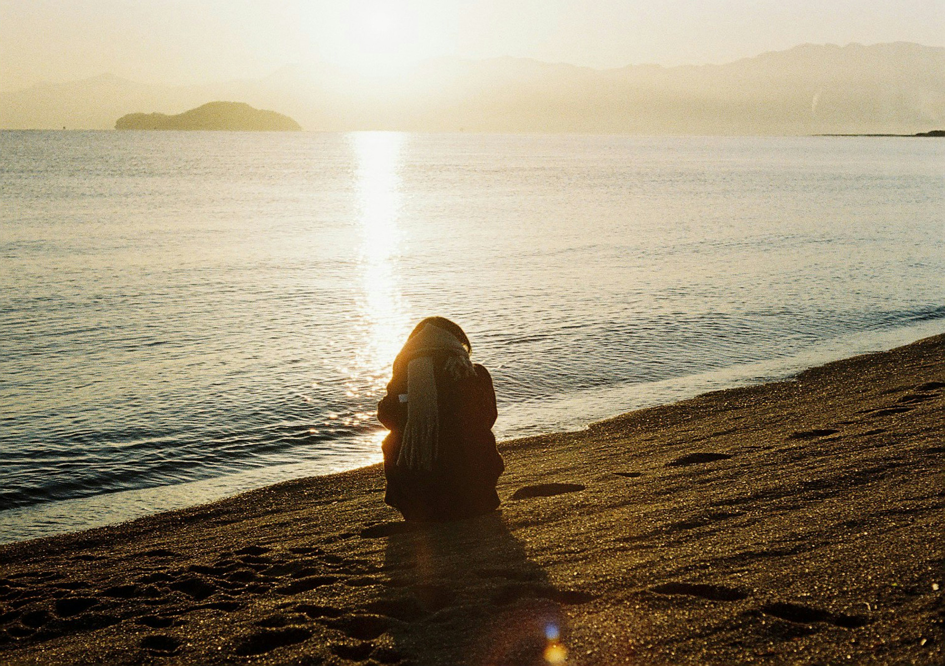 海辺で夕日を眺める女性のシルエット