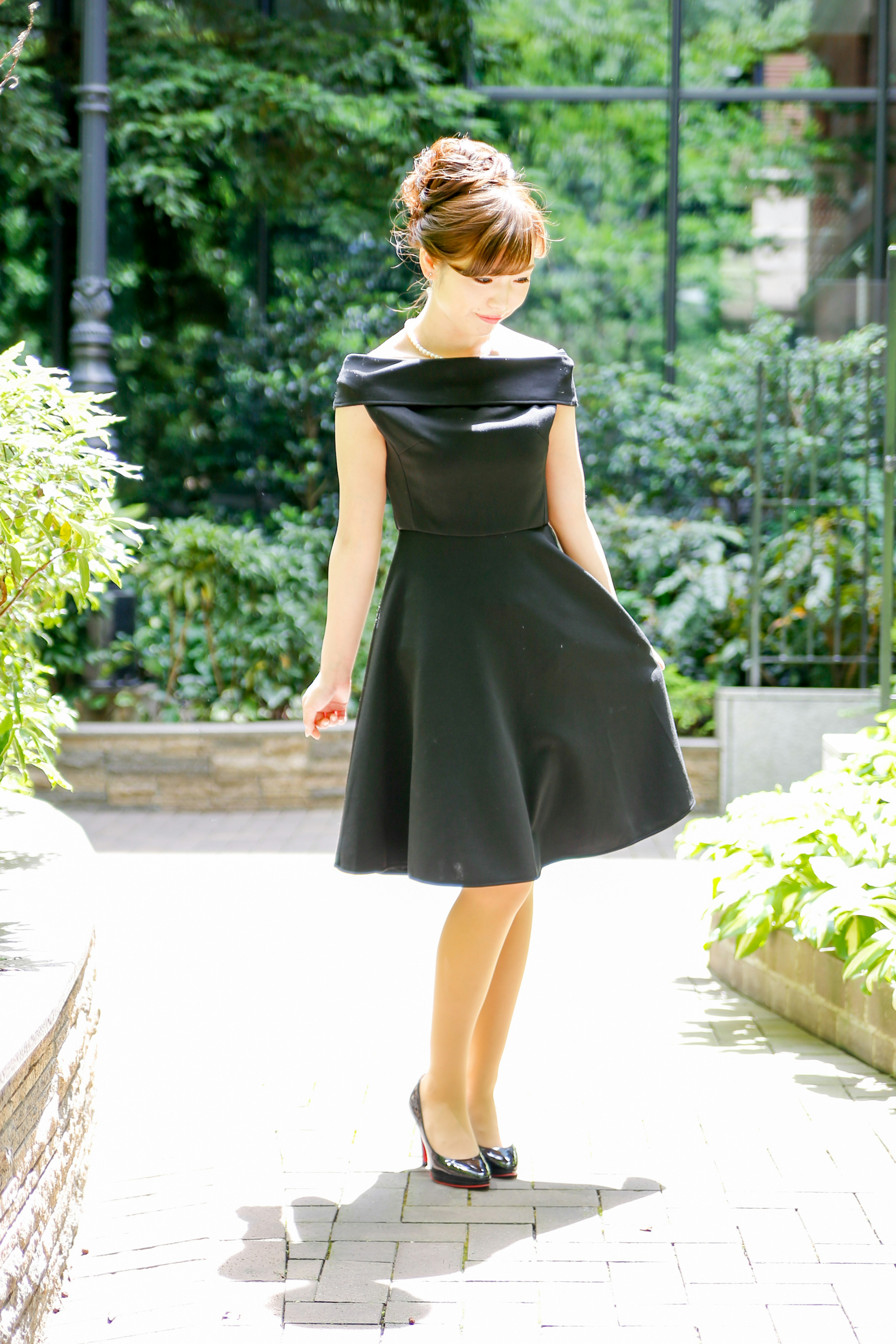 Una mujer en un vestido negro posa en un jardín verde