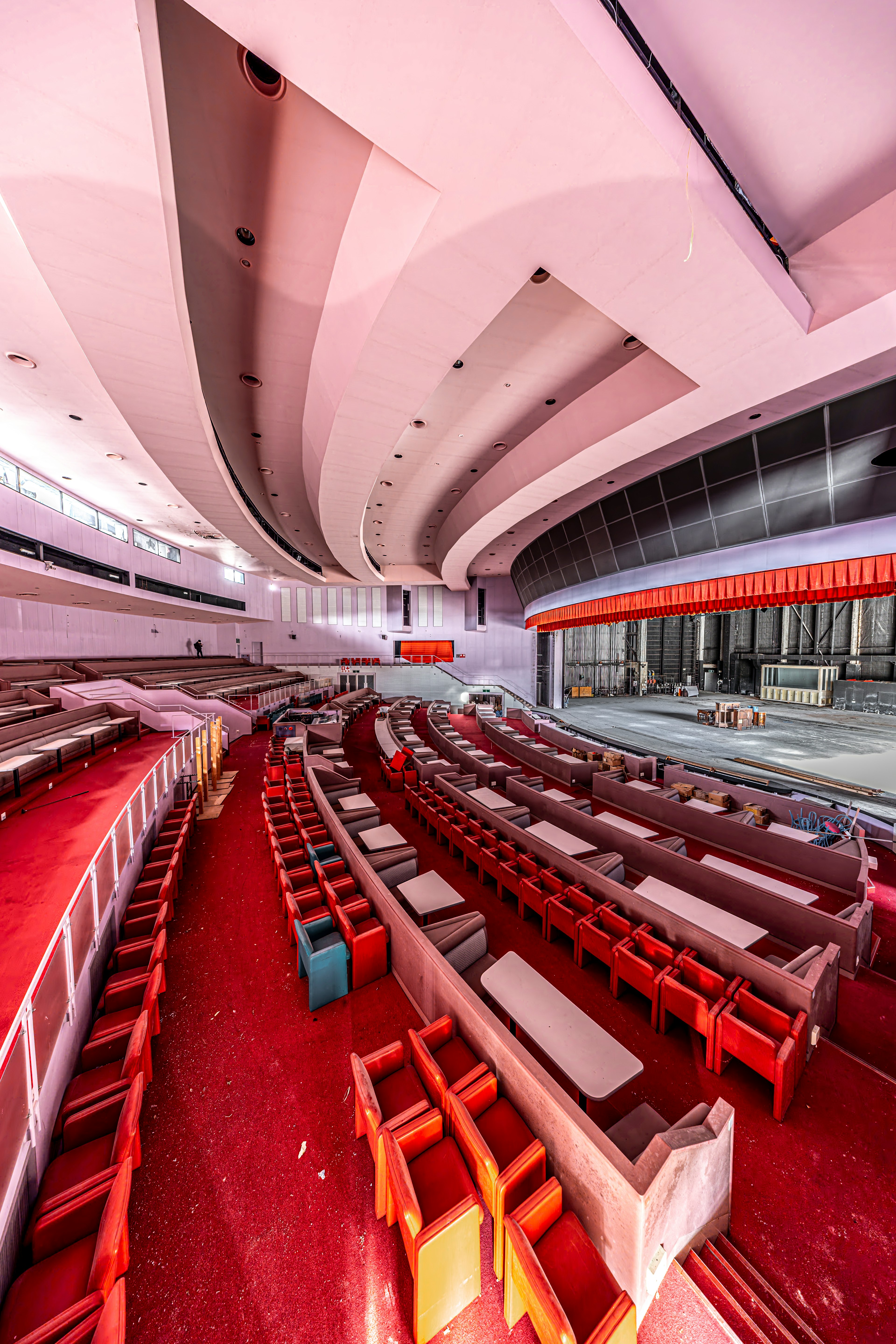 Interior of an abandoned theater featuring red seats and curved ceiling