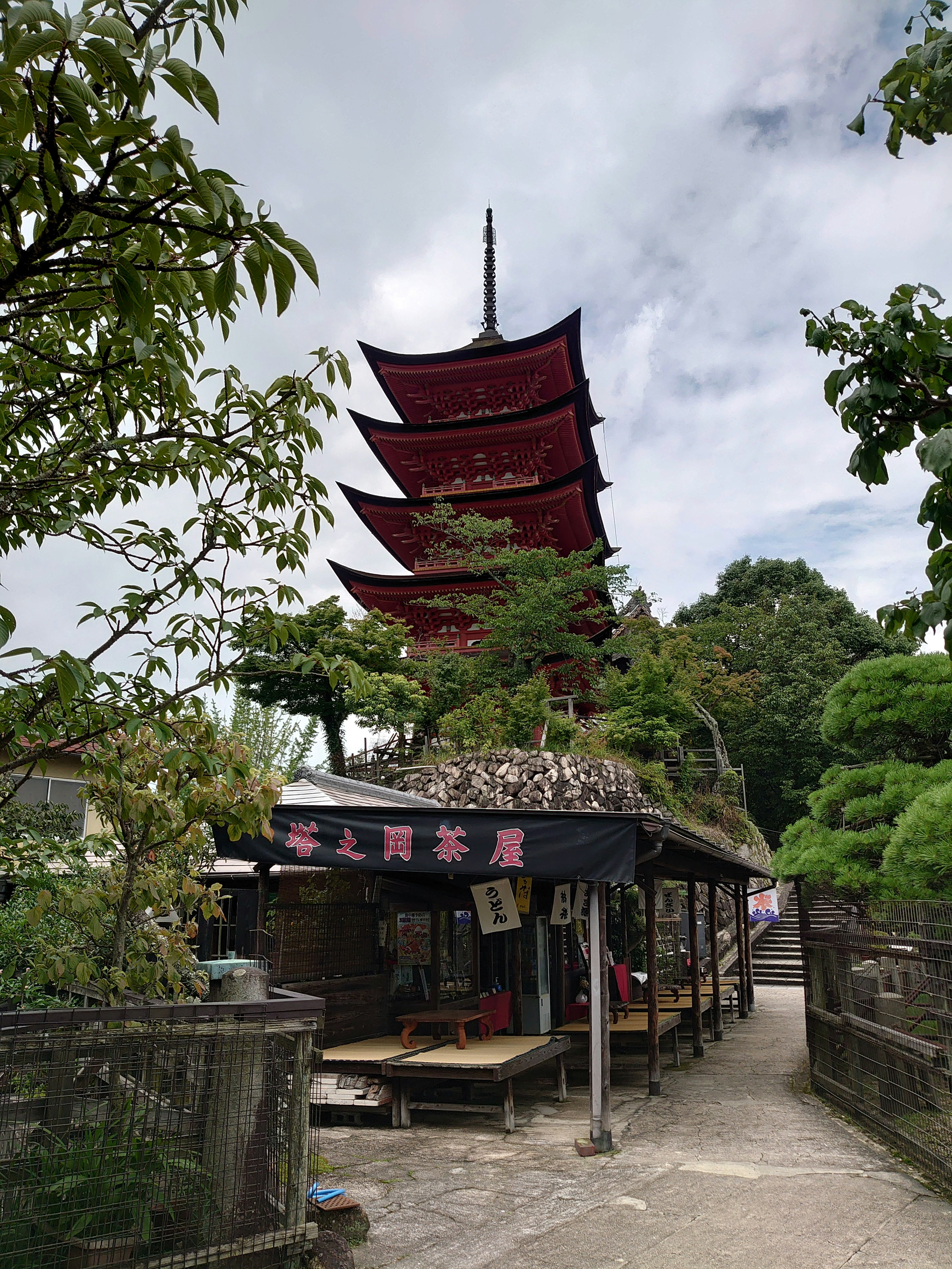 Pagoda rossa a cinque piani circondata da una vegetazione lussureggiante