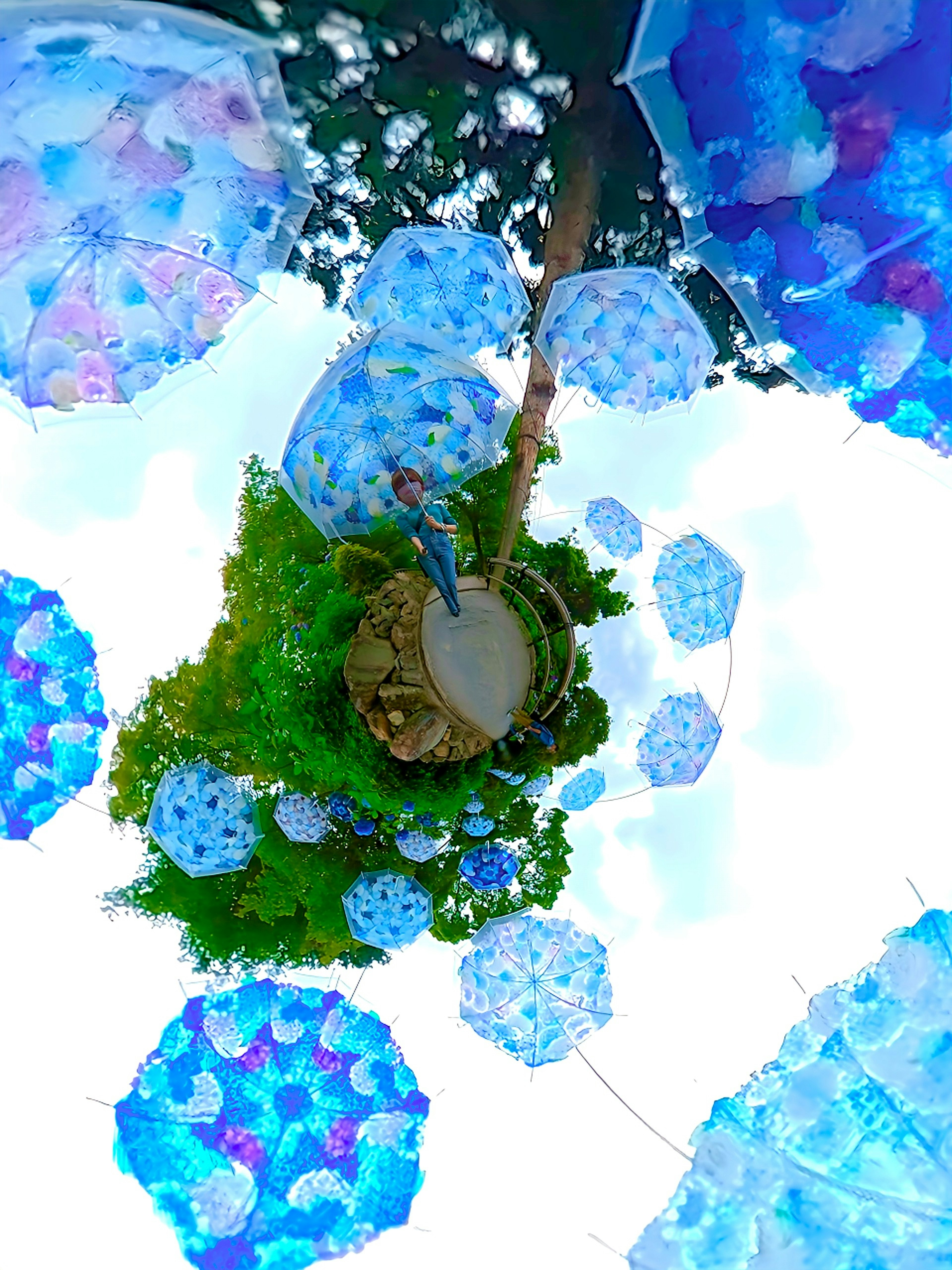 Une vue d'une île verte entourée de parapluies bleus et blancs avec une personne au centre