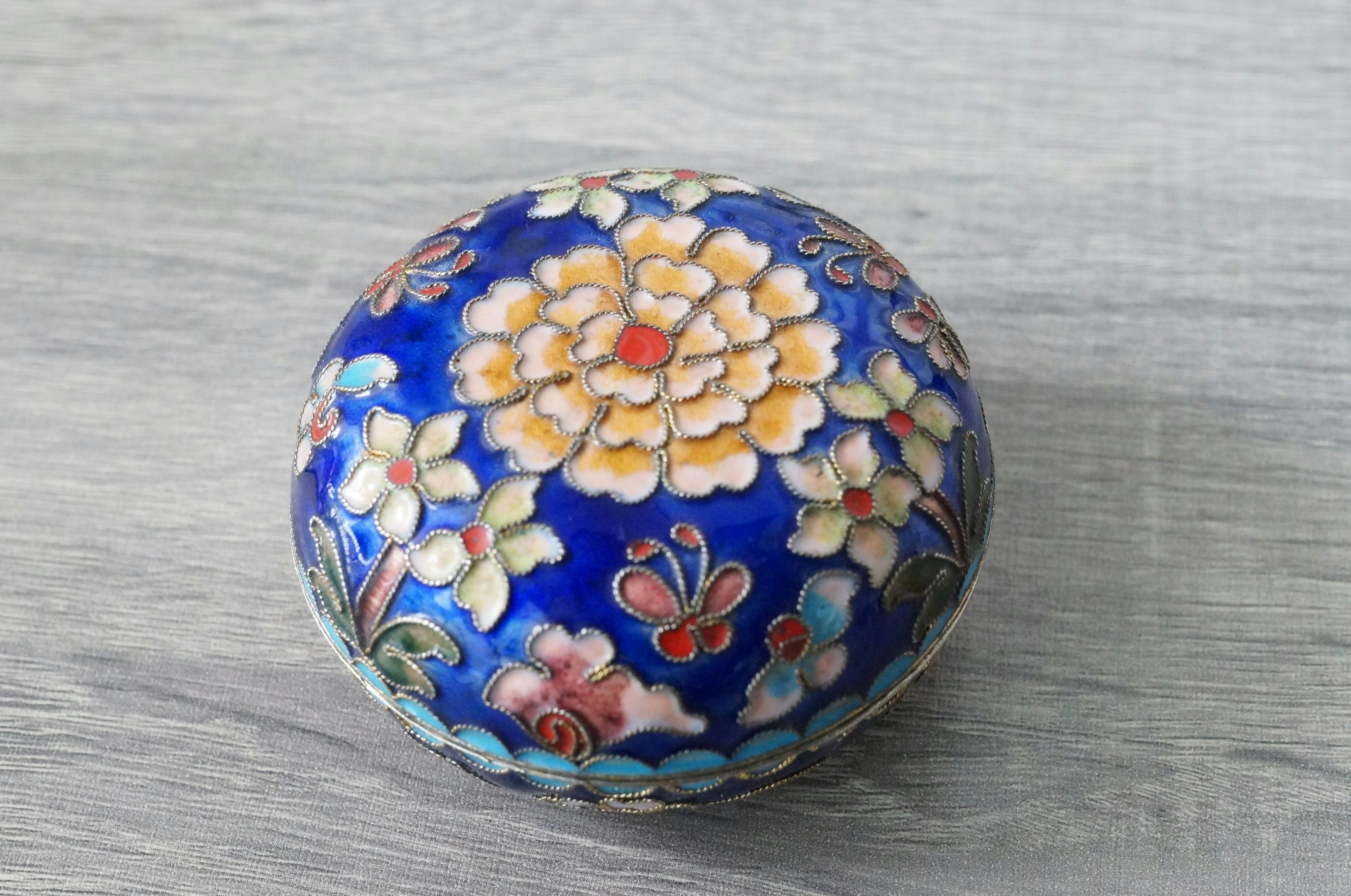 Round decorative box with floral patterns on a blue background