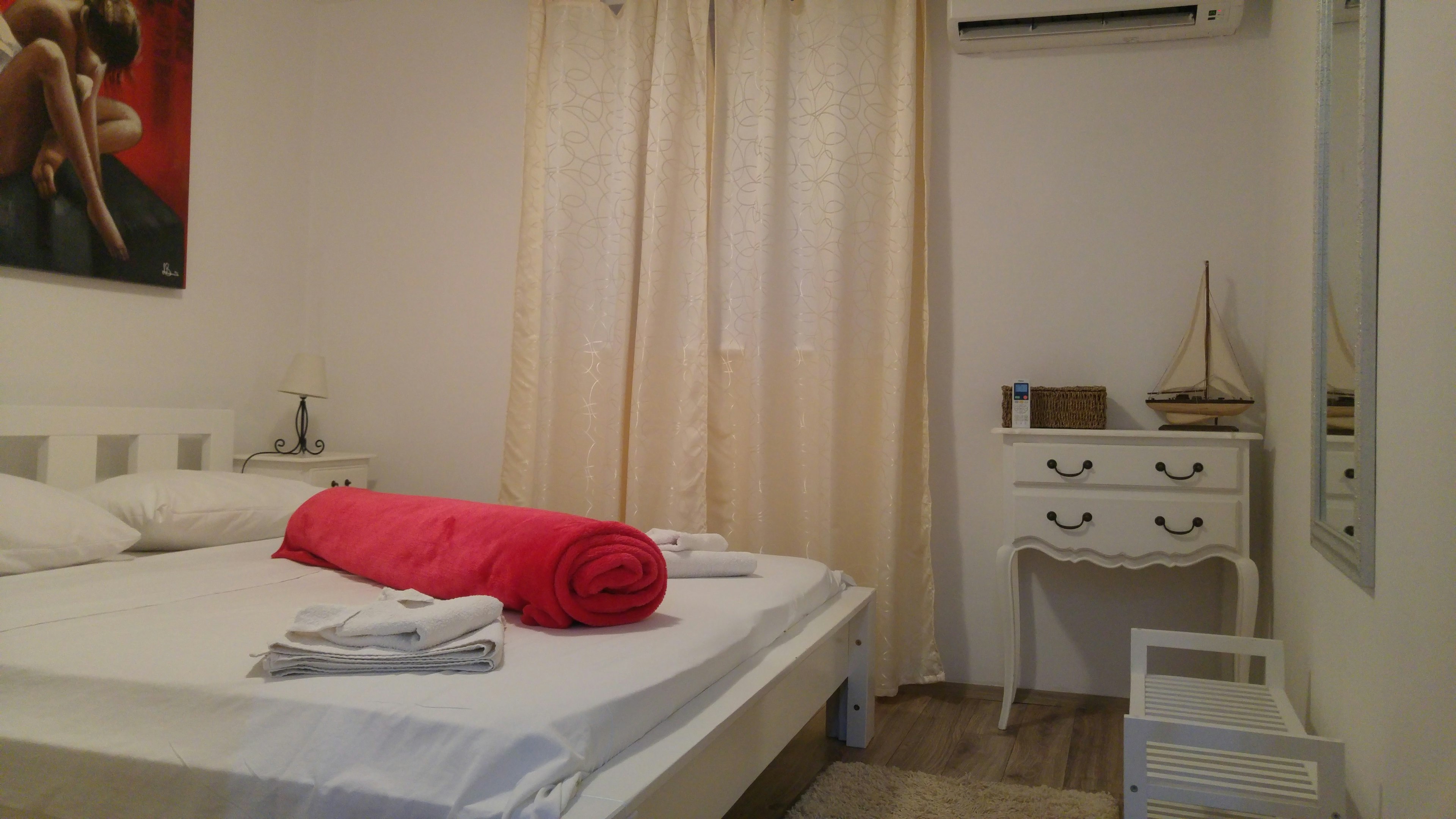 Intérieur de chambre à coucher lumineux et simple avec un lit blanc et des serviettes rouges