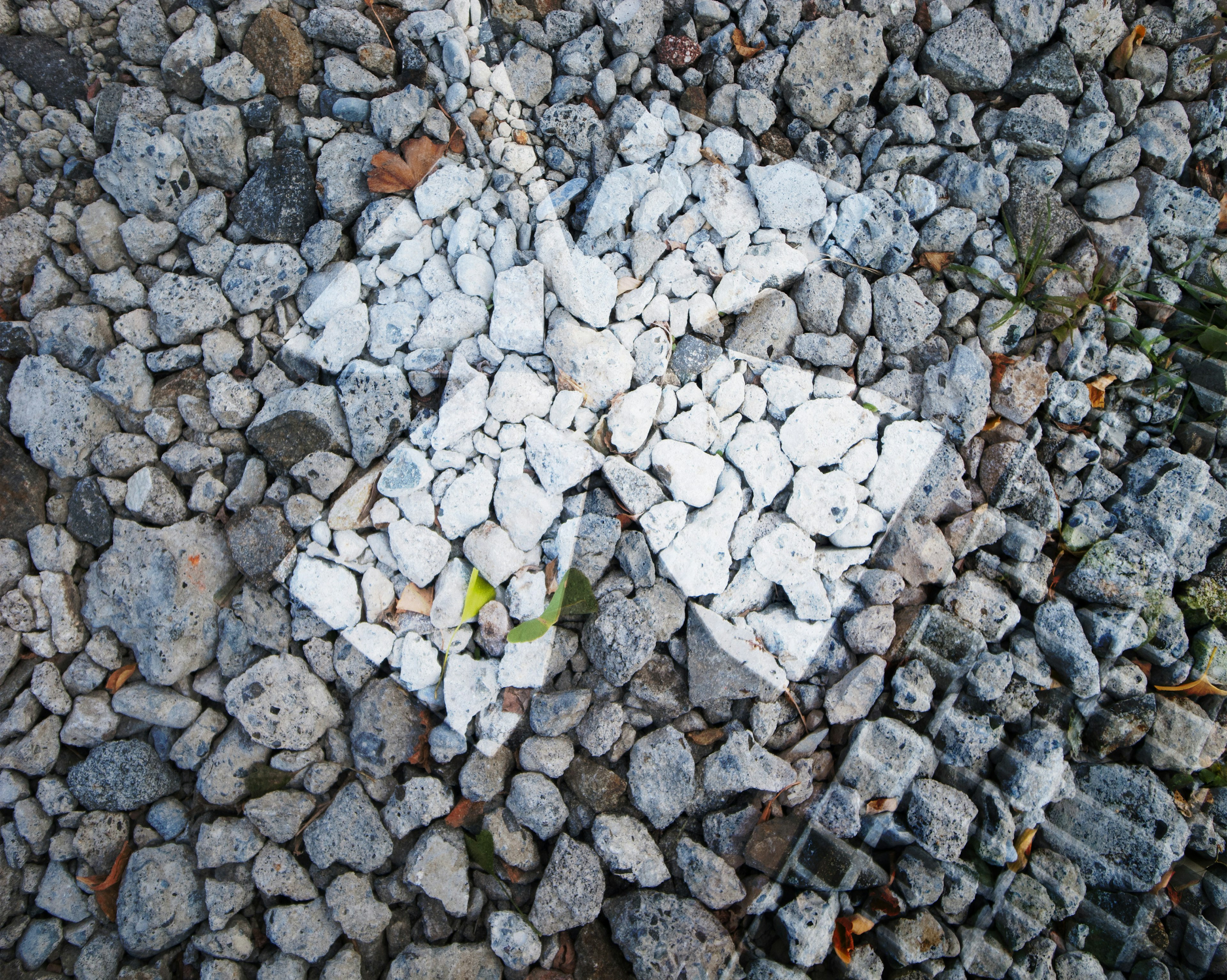 Motif de croix blanche fait de pierres sur une surface rocheuse