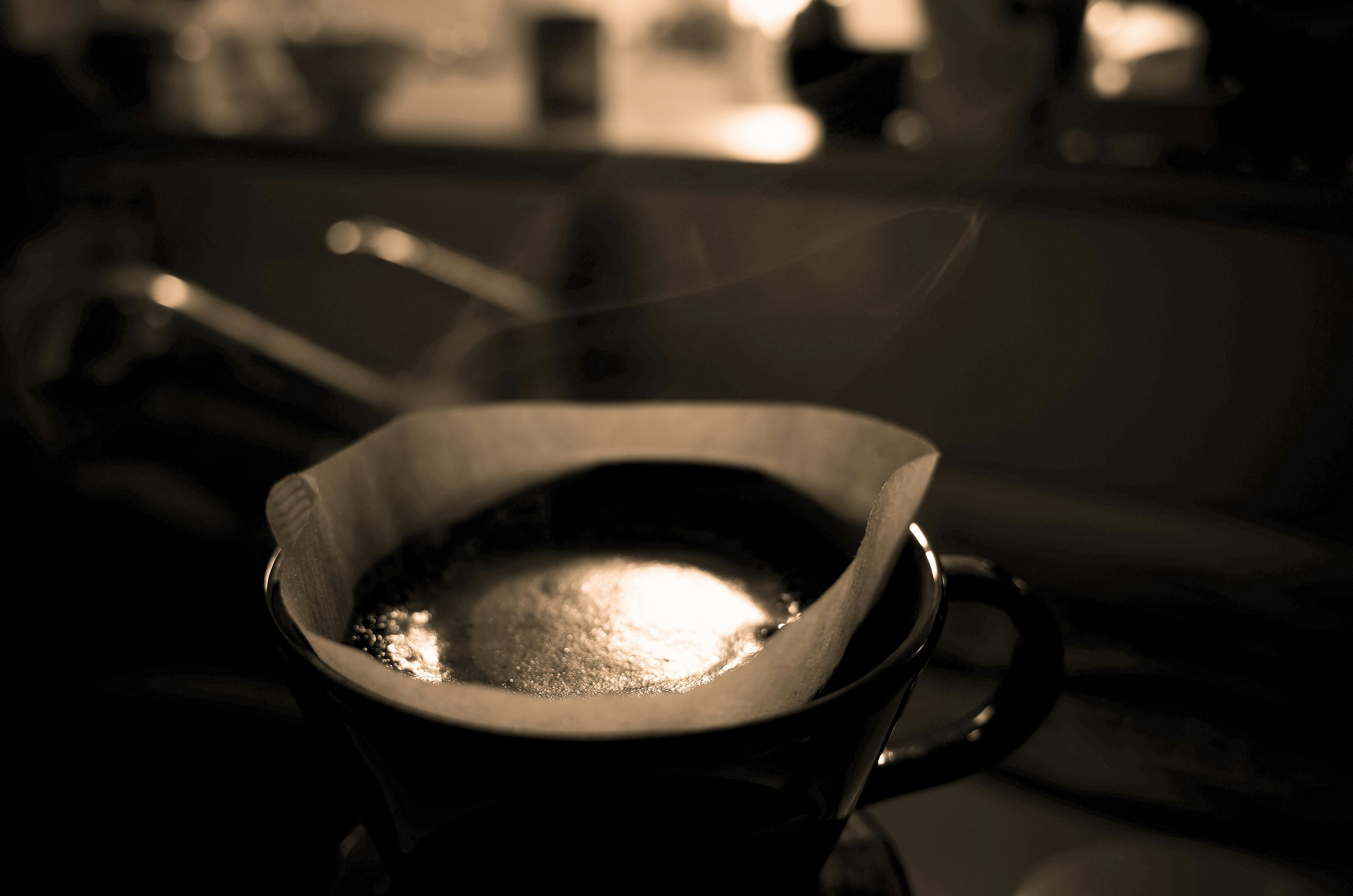 Foto penyaring kopi dengan kopi yang sedang diseduh dan uap yang naik