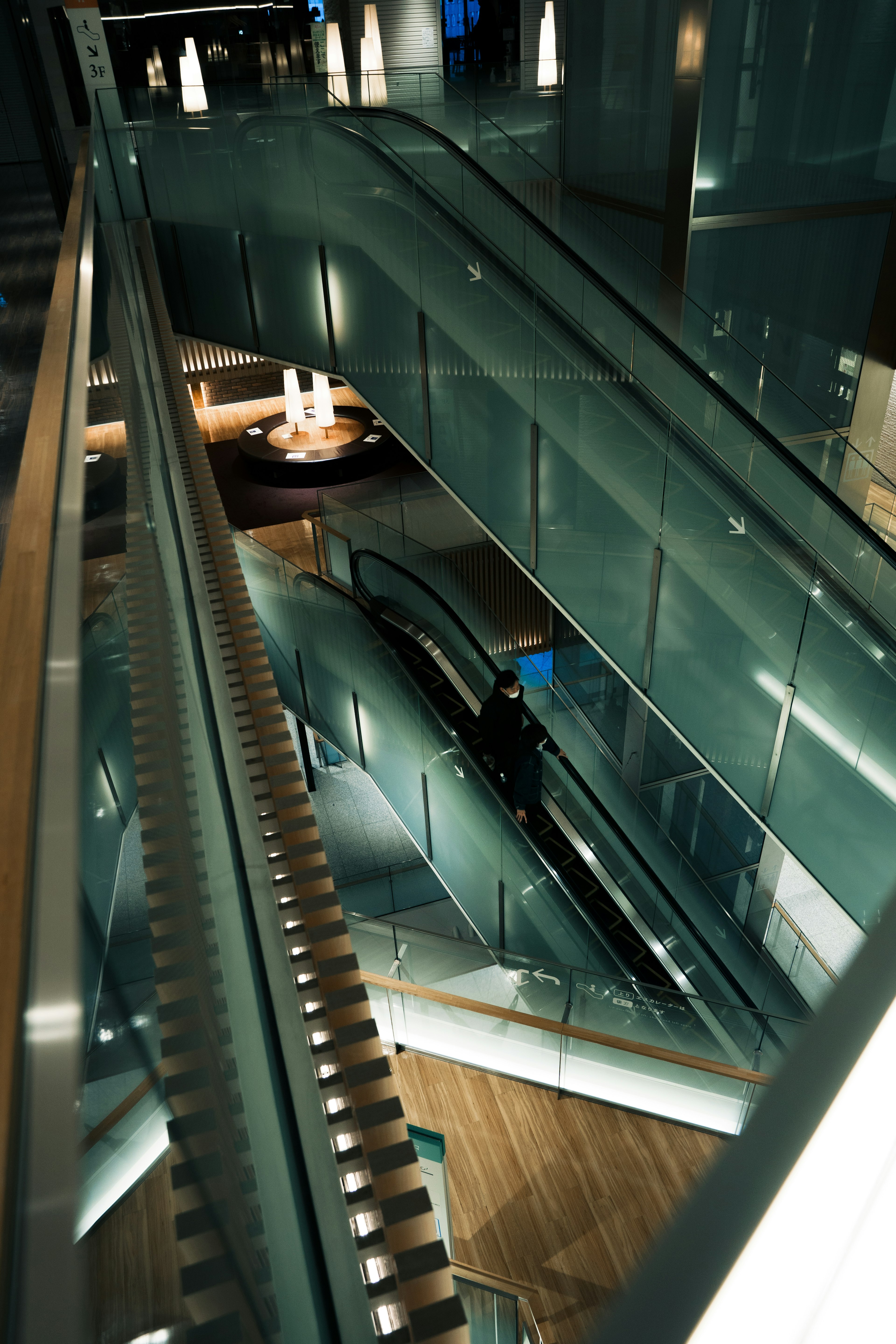 Modern glass escalators with wooden flooring in an interior space