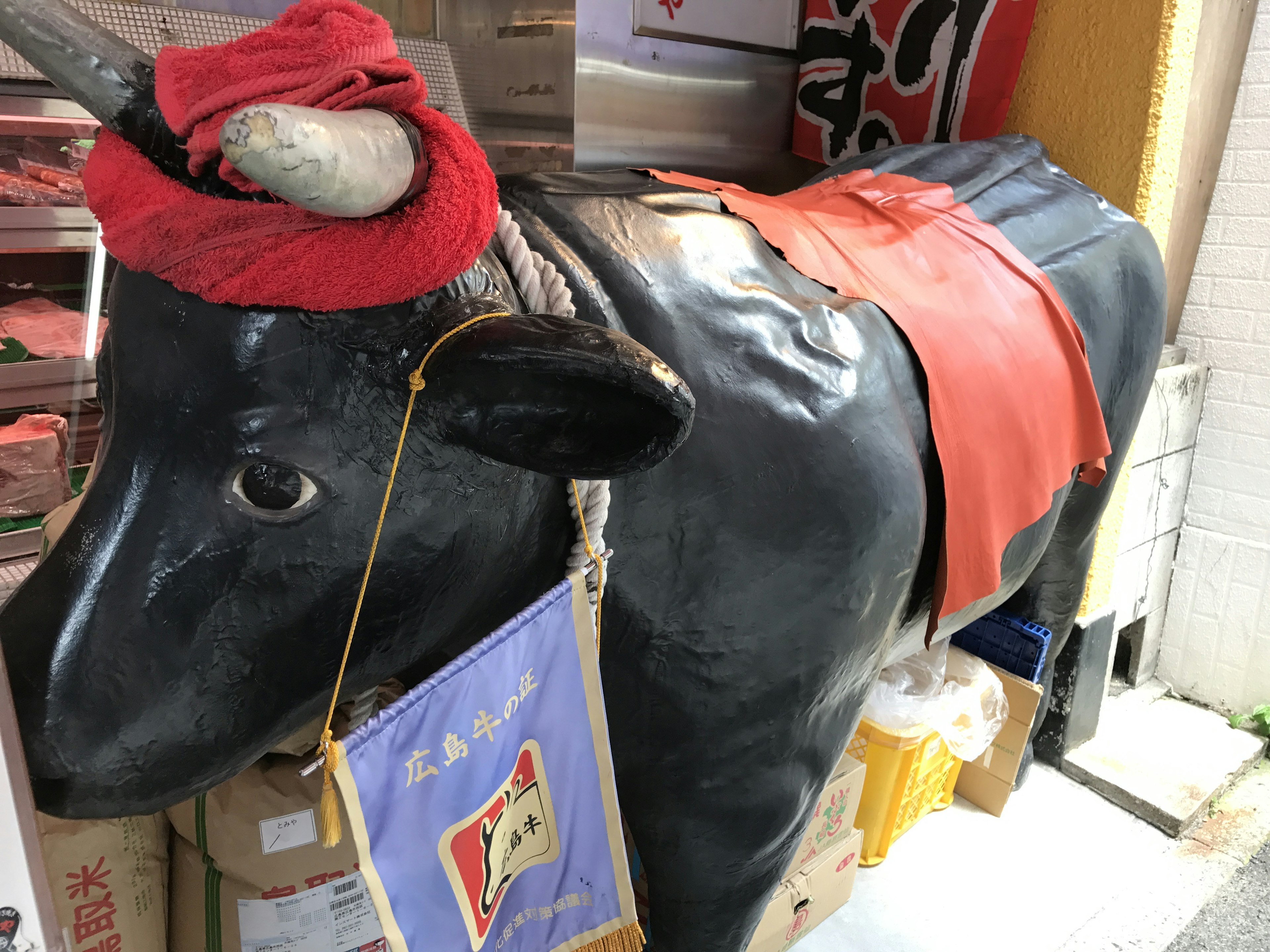 Black cow sculpture adorned with red fabric and hat