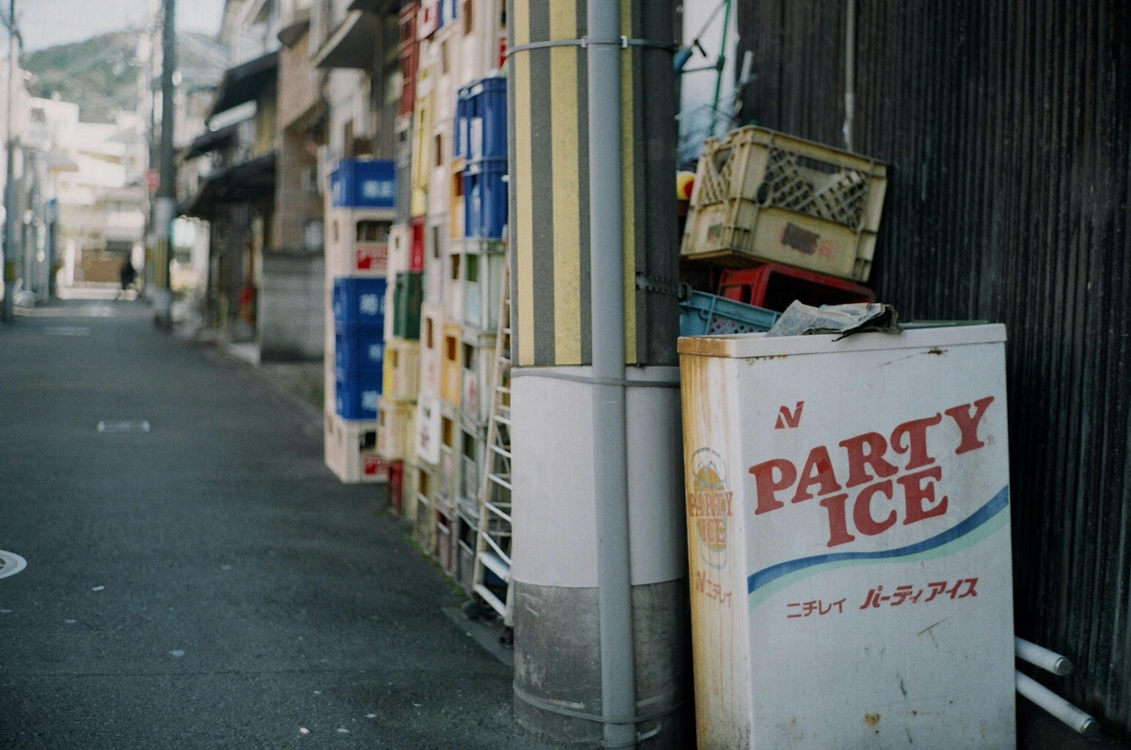 狭い路地に置かれたパーティーアイスの冷凍庫と周囲の色とりどりのボックス