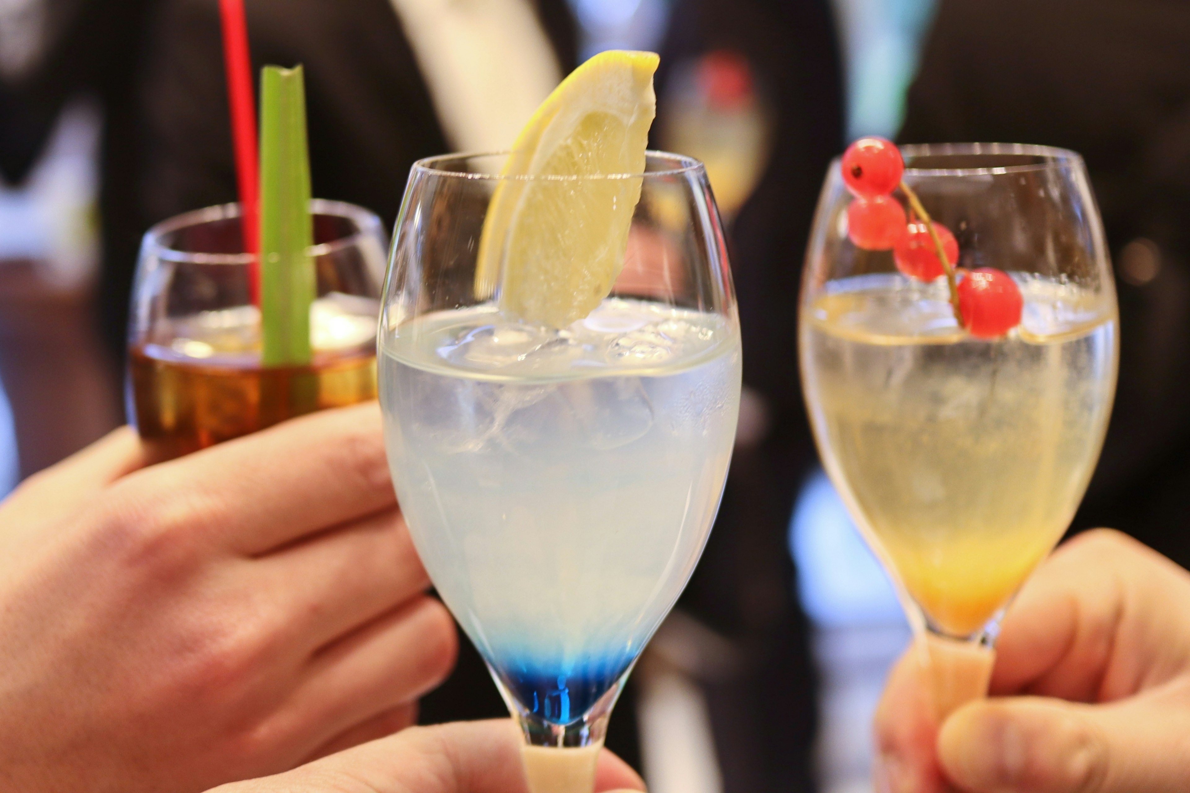 Colorful cocktails held in hands with garnishes