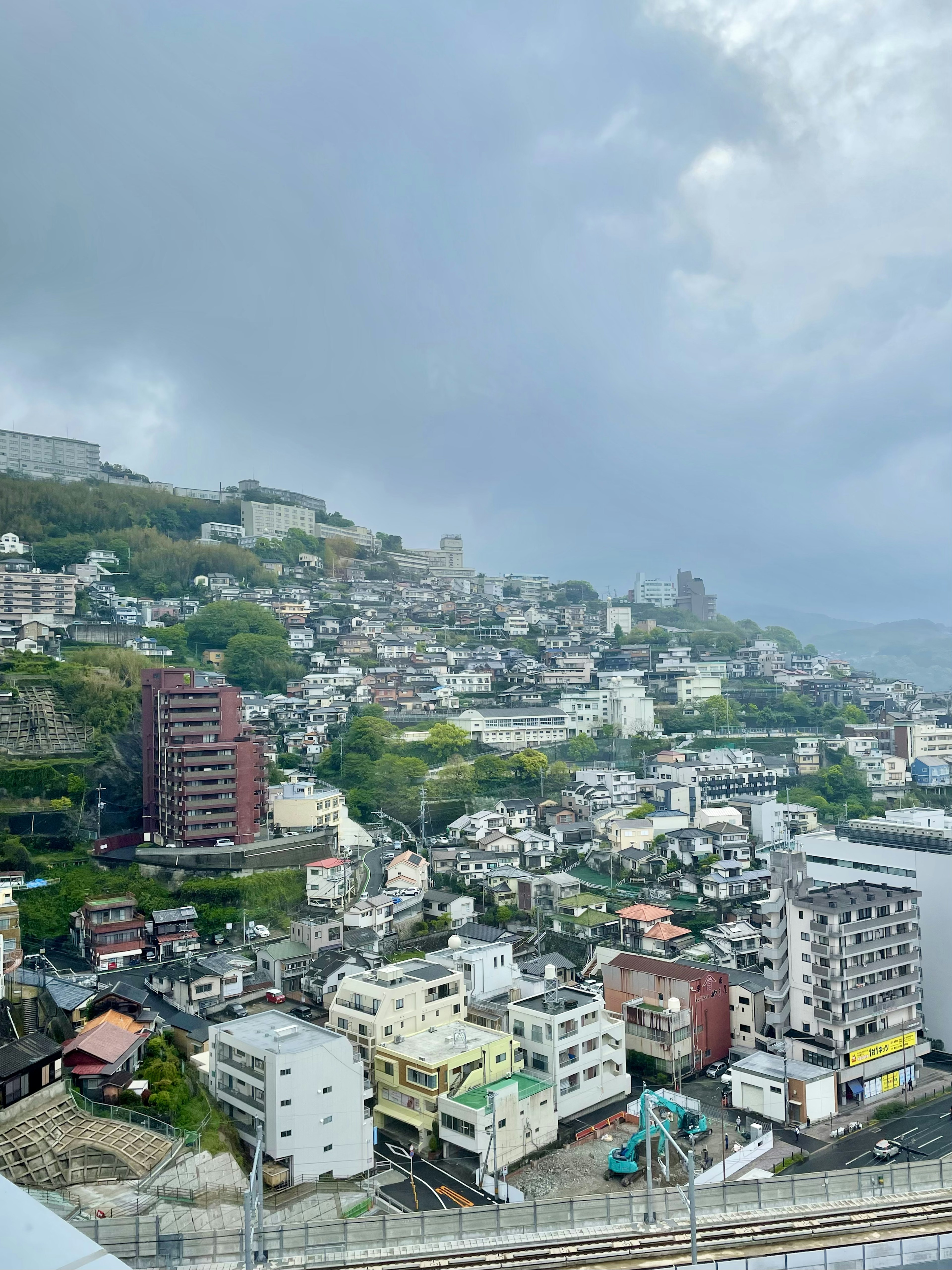 Cityscape with buildings on a hillside under a cloudy sky