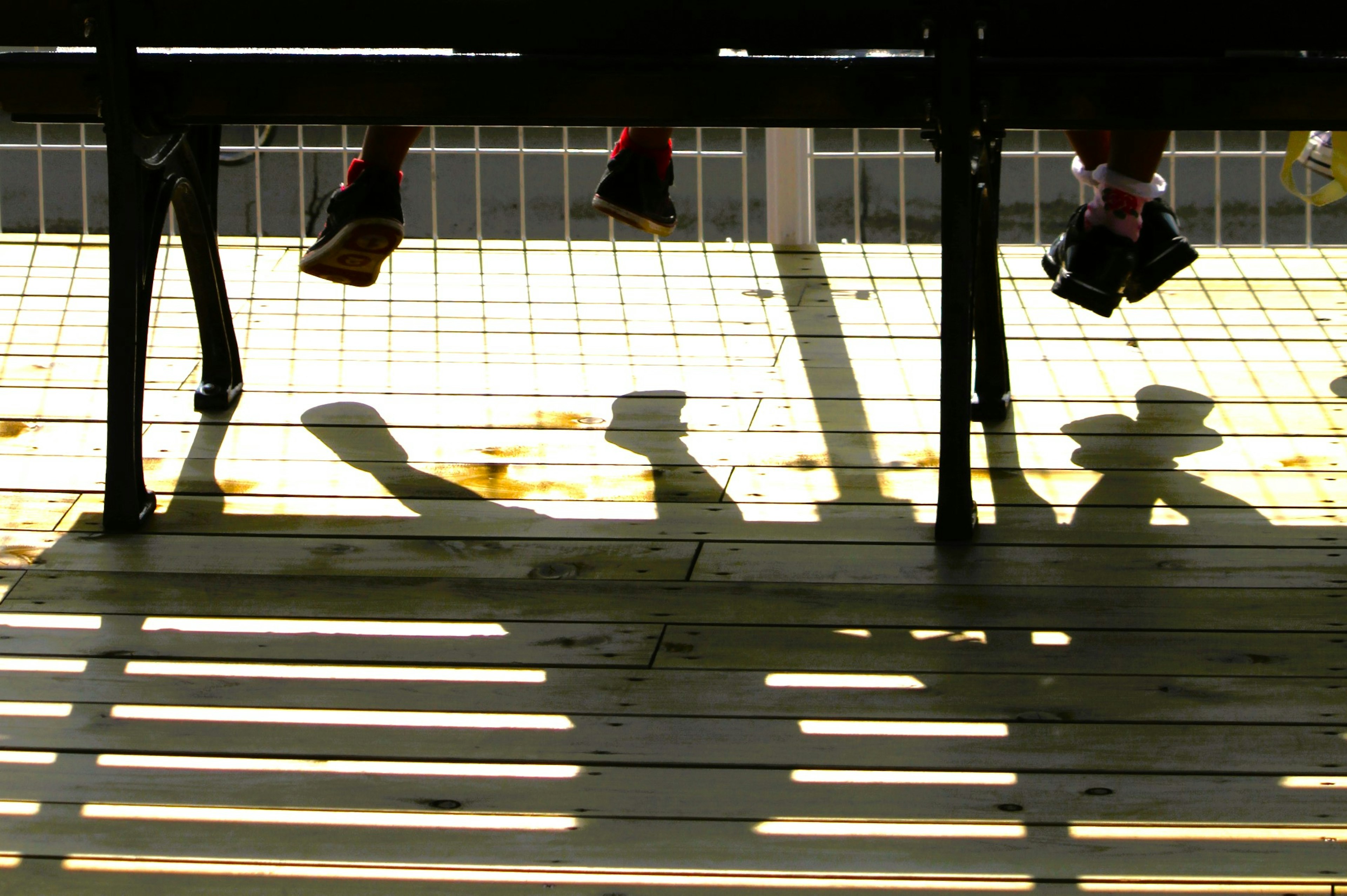 Children's feet casting shadows on a wooden floor