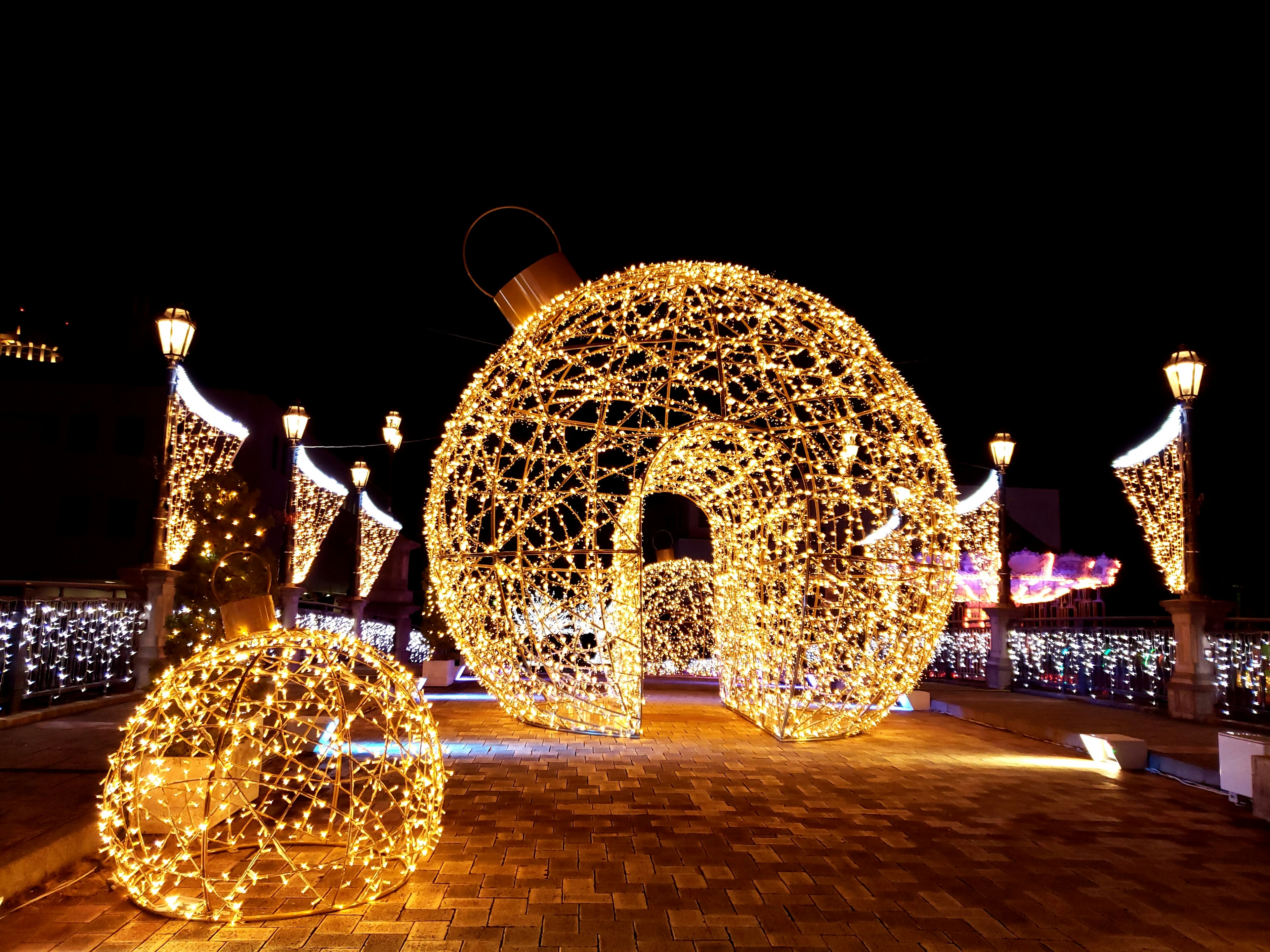 Large illuminated Christmas ornament and smaller ornament in a festive setting