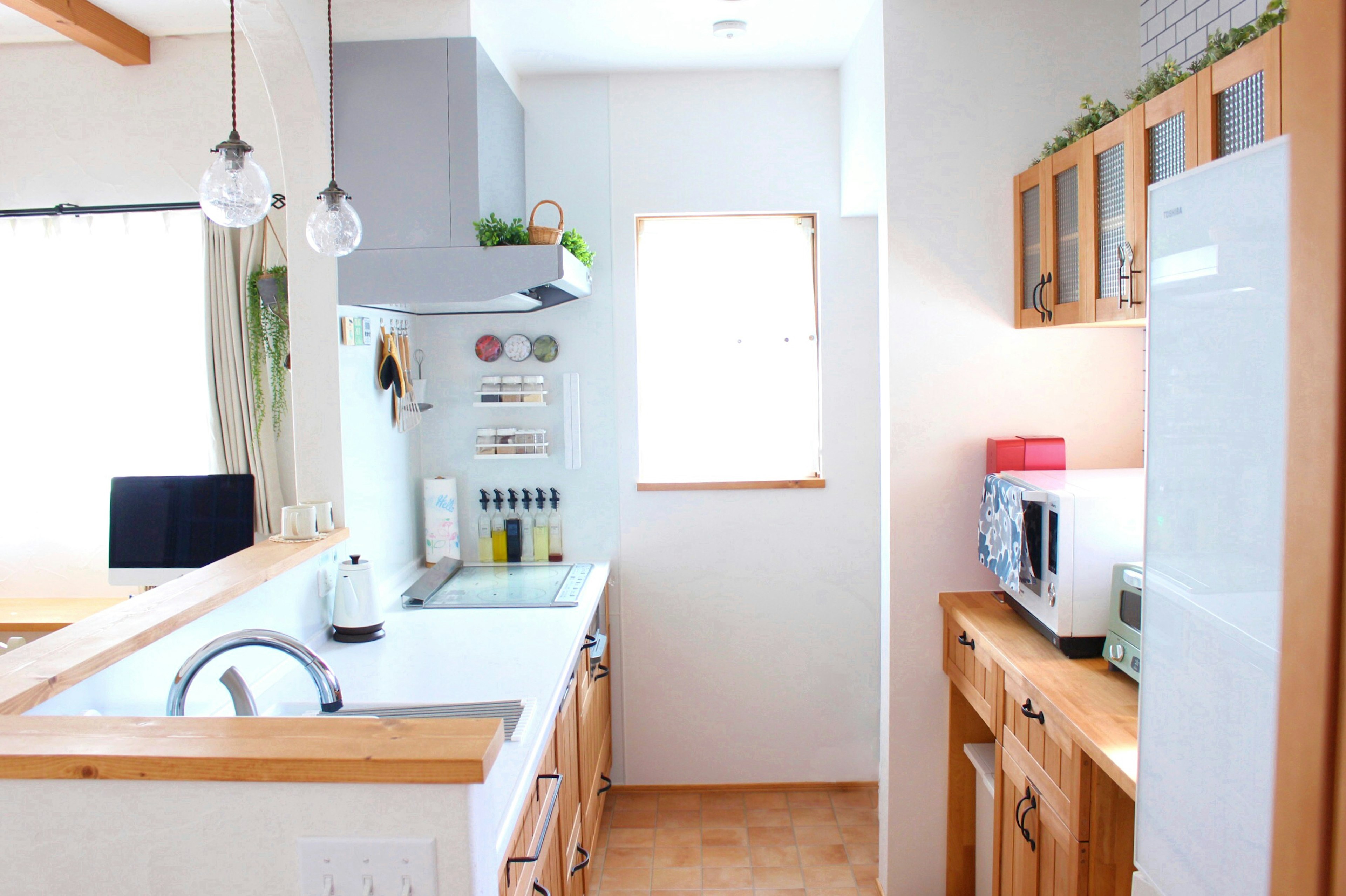 Escena de cocina brillante con fregadero blanco y armarios de madera luz natural que entra por la ventana