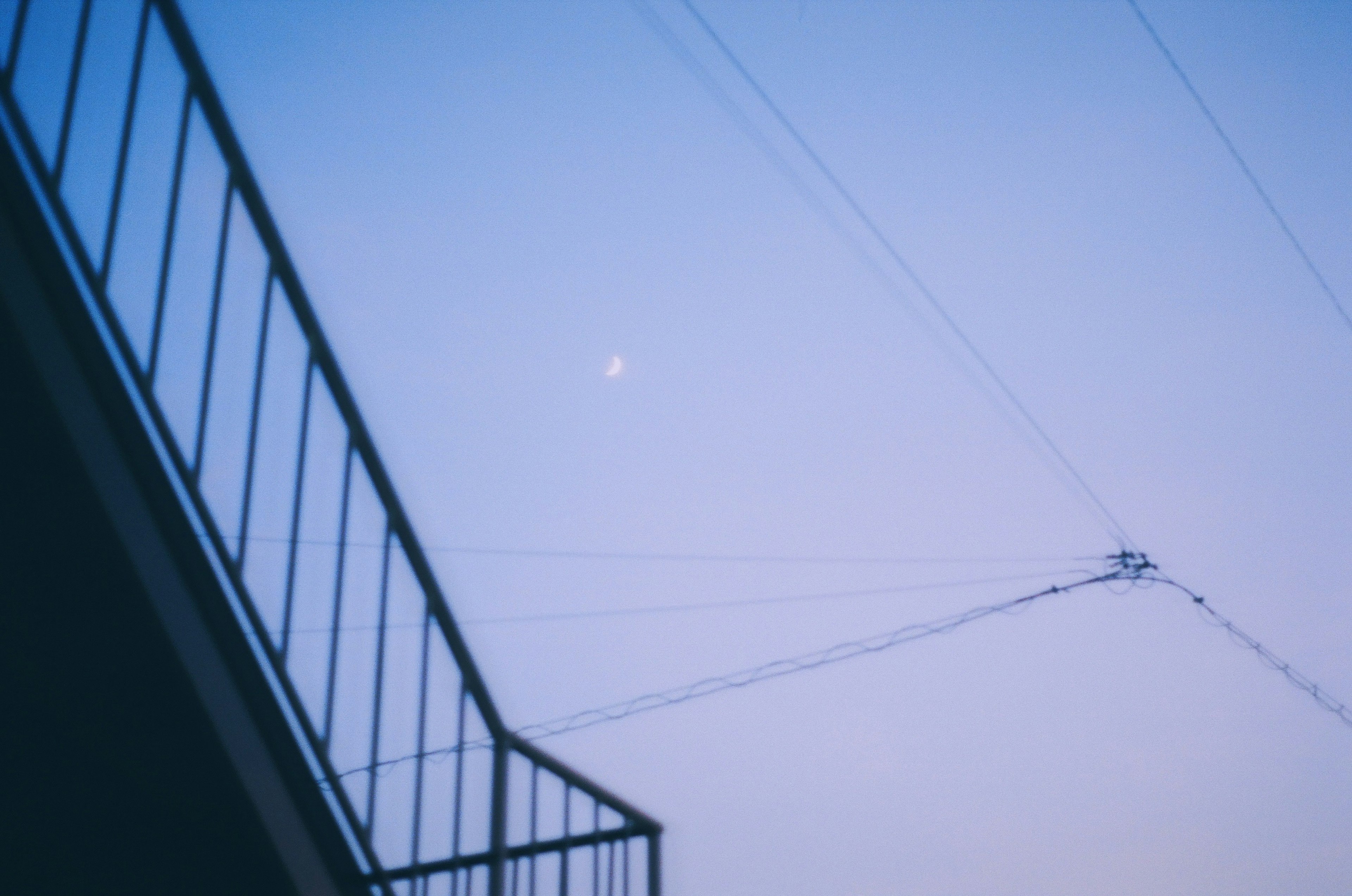 Pemandangan bulan di langit biru dengan kabel listrik