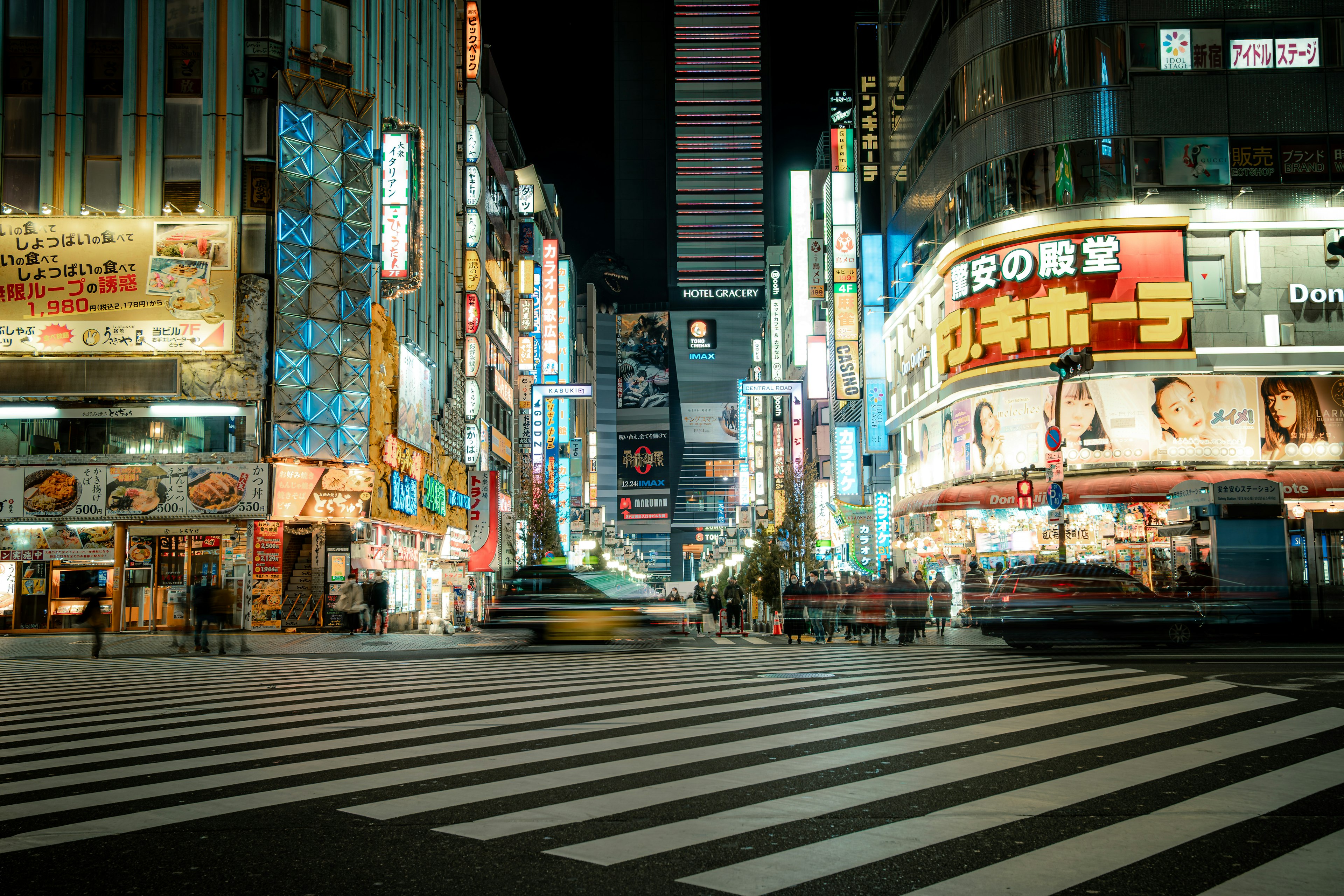 Crosswalk in a bustling city street at night with neon signs