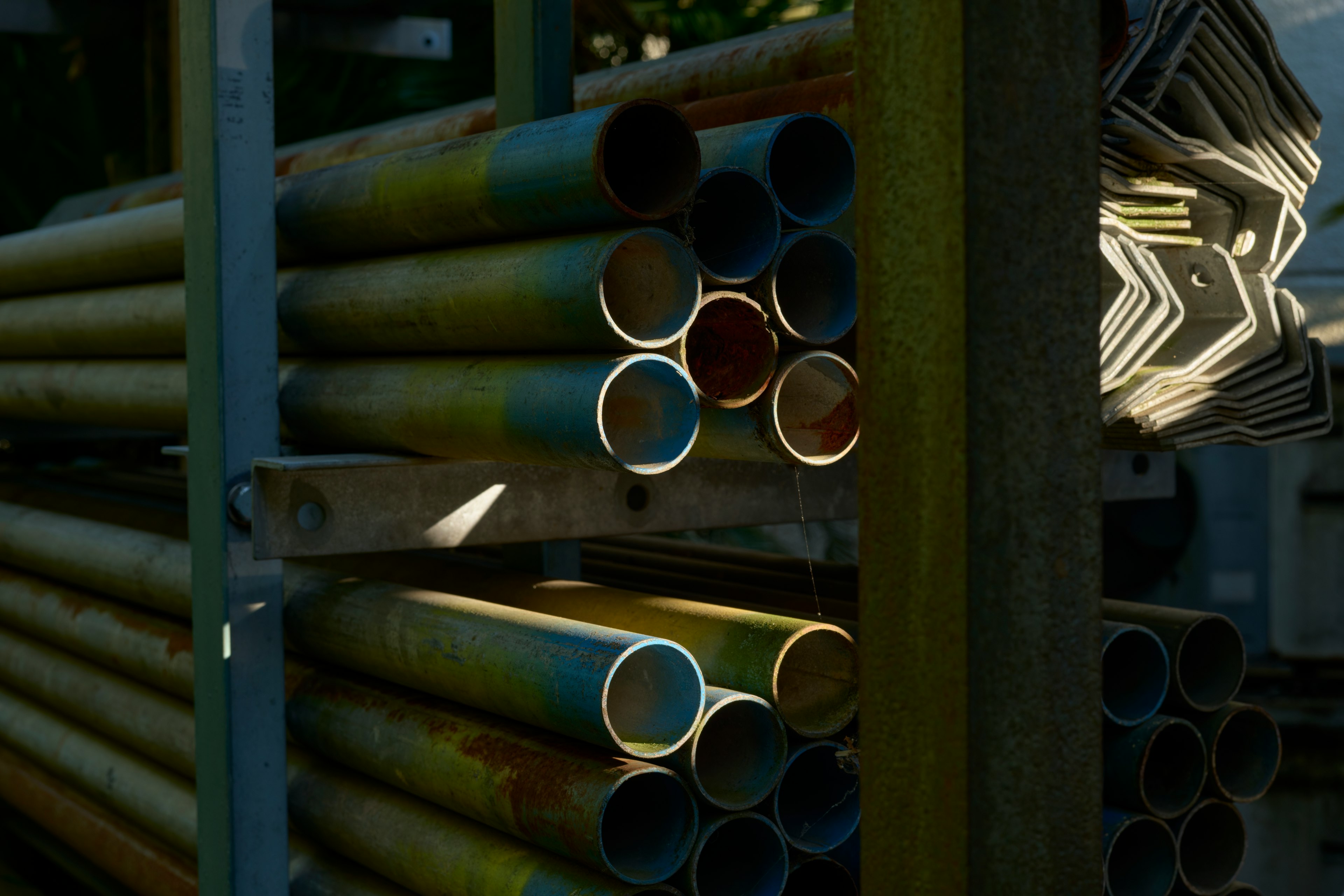 Image of stacked metal pipes with unique blue painted ends and shadows