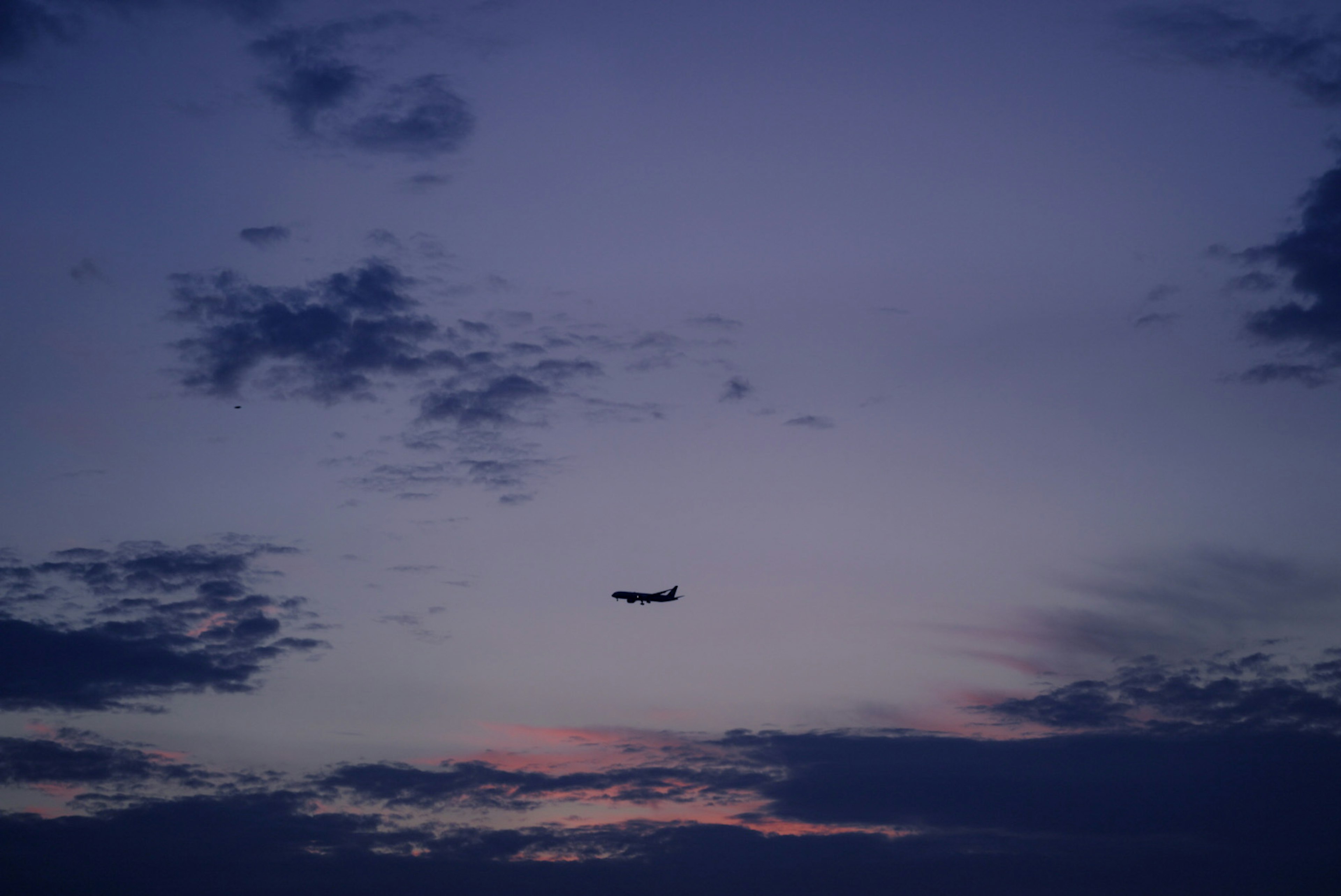 夕焼けの空に飛行機が浮かぶシルエット