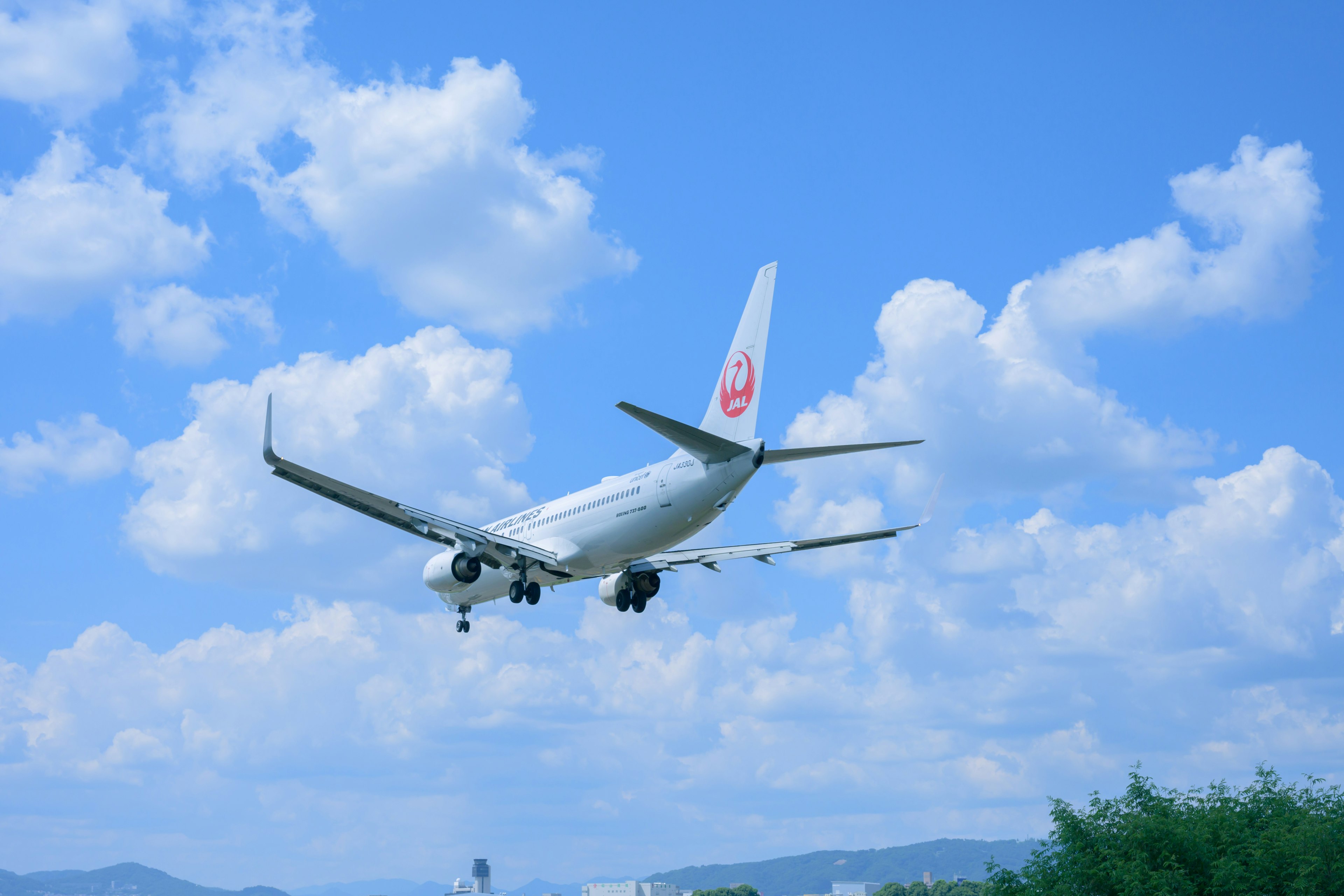 Flugzeug fliegt unter einem blauen Himmel mit flauschigen Wolken