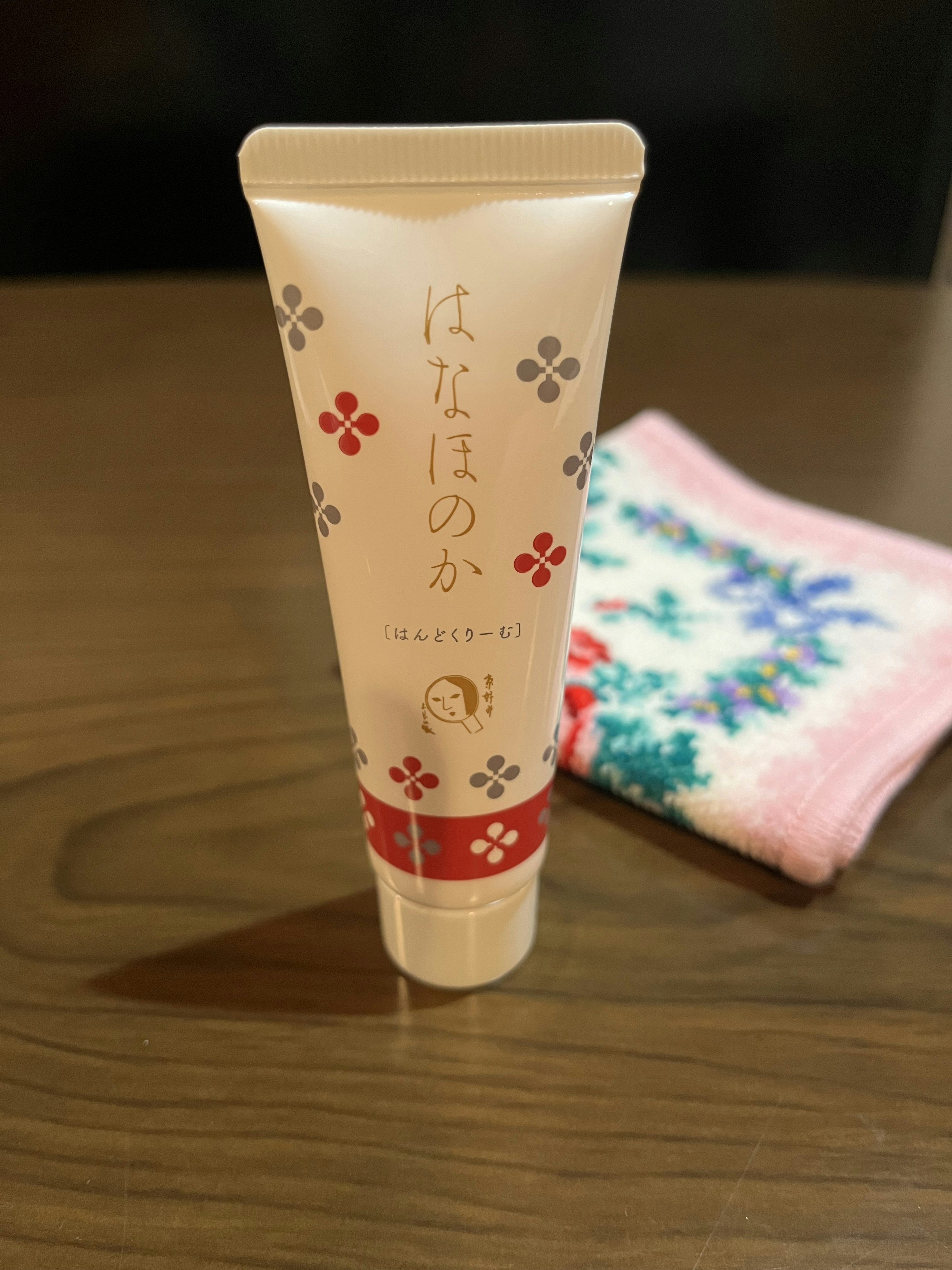 Cream tube with floral design beside a colorful towel