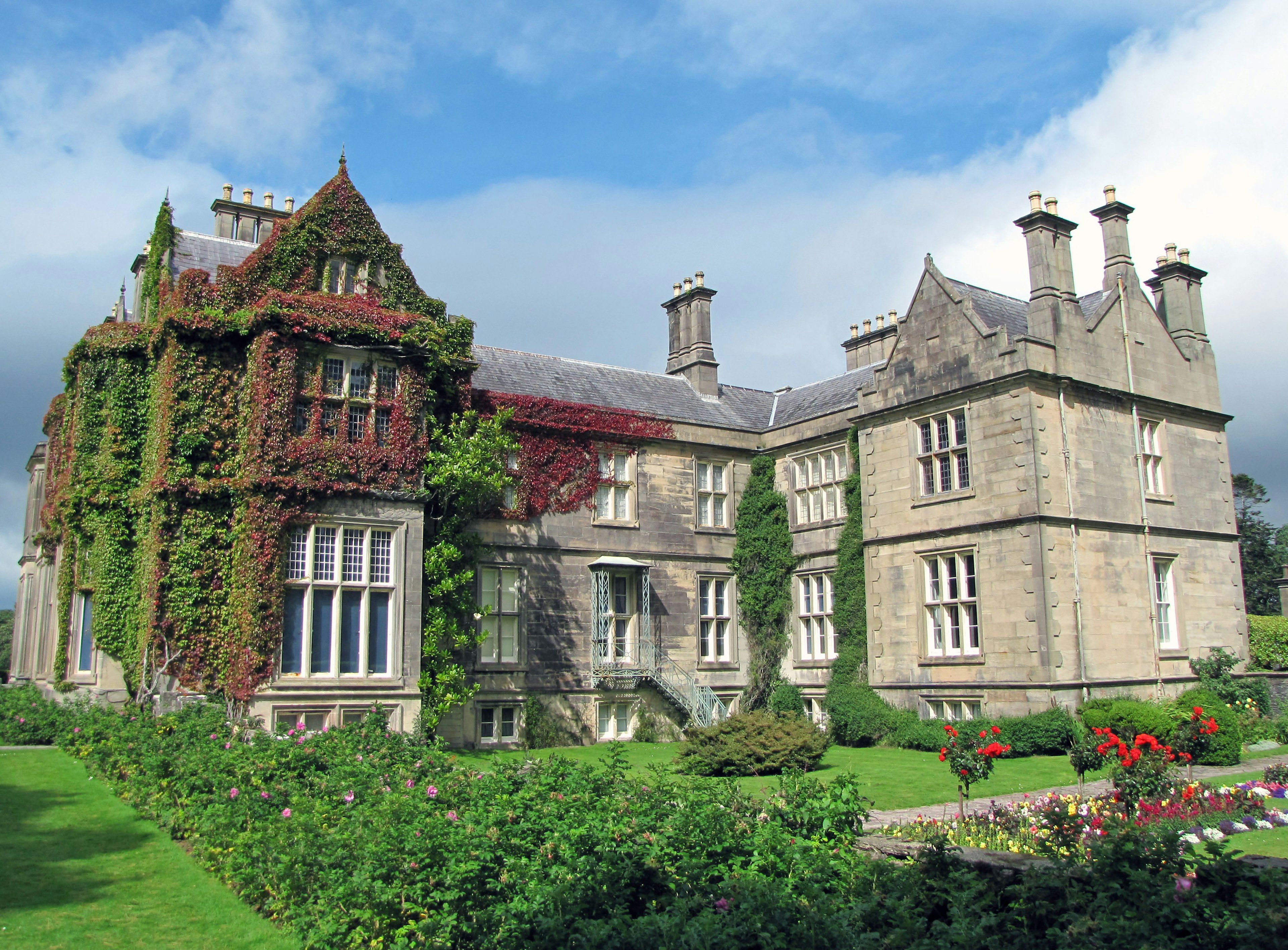 Historic stone mansion surrounded by a beautiful garden adorned with greenery