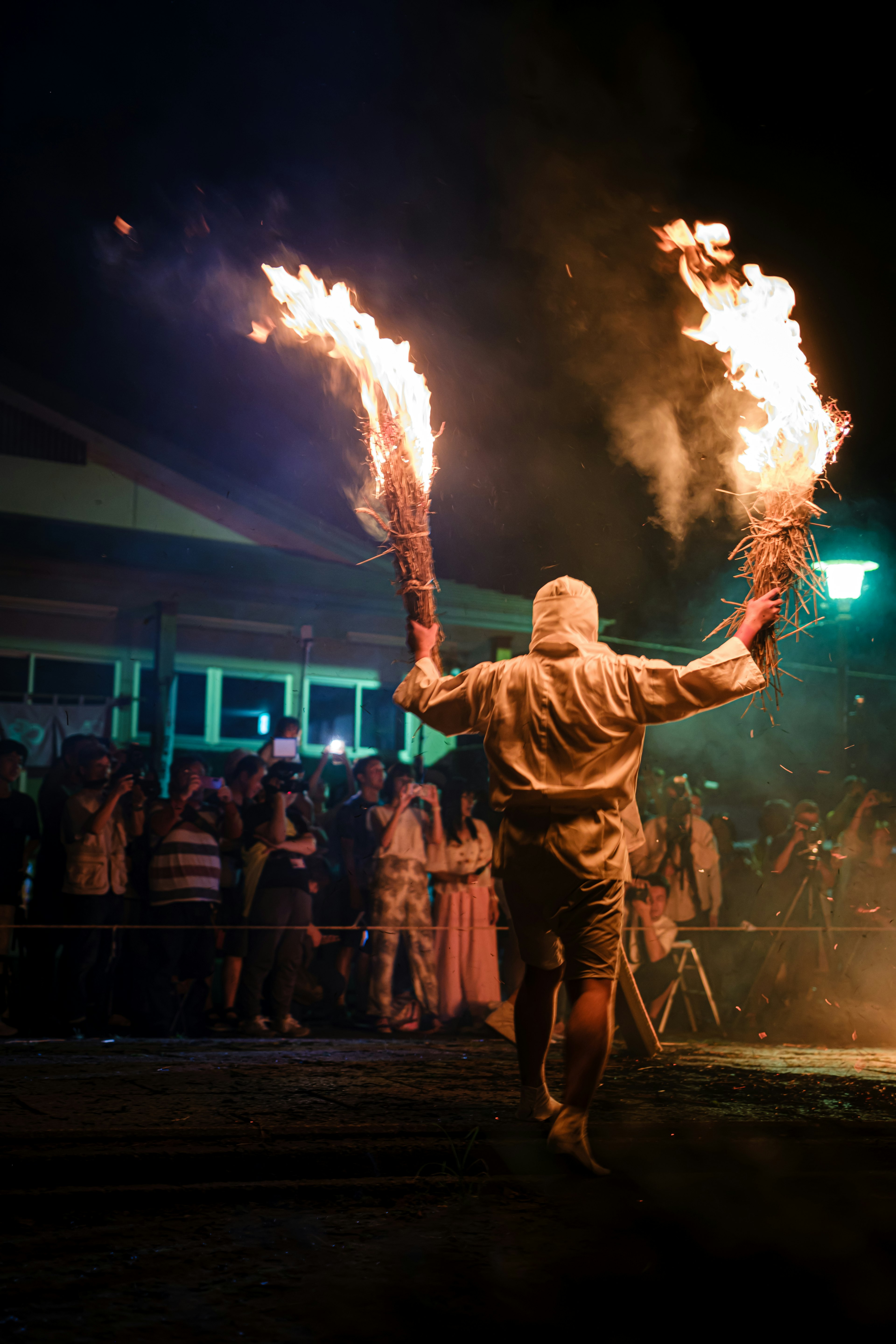 Artista con antorchas de fuego entreteniendo a una audiencia de noche