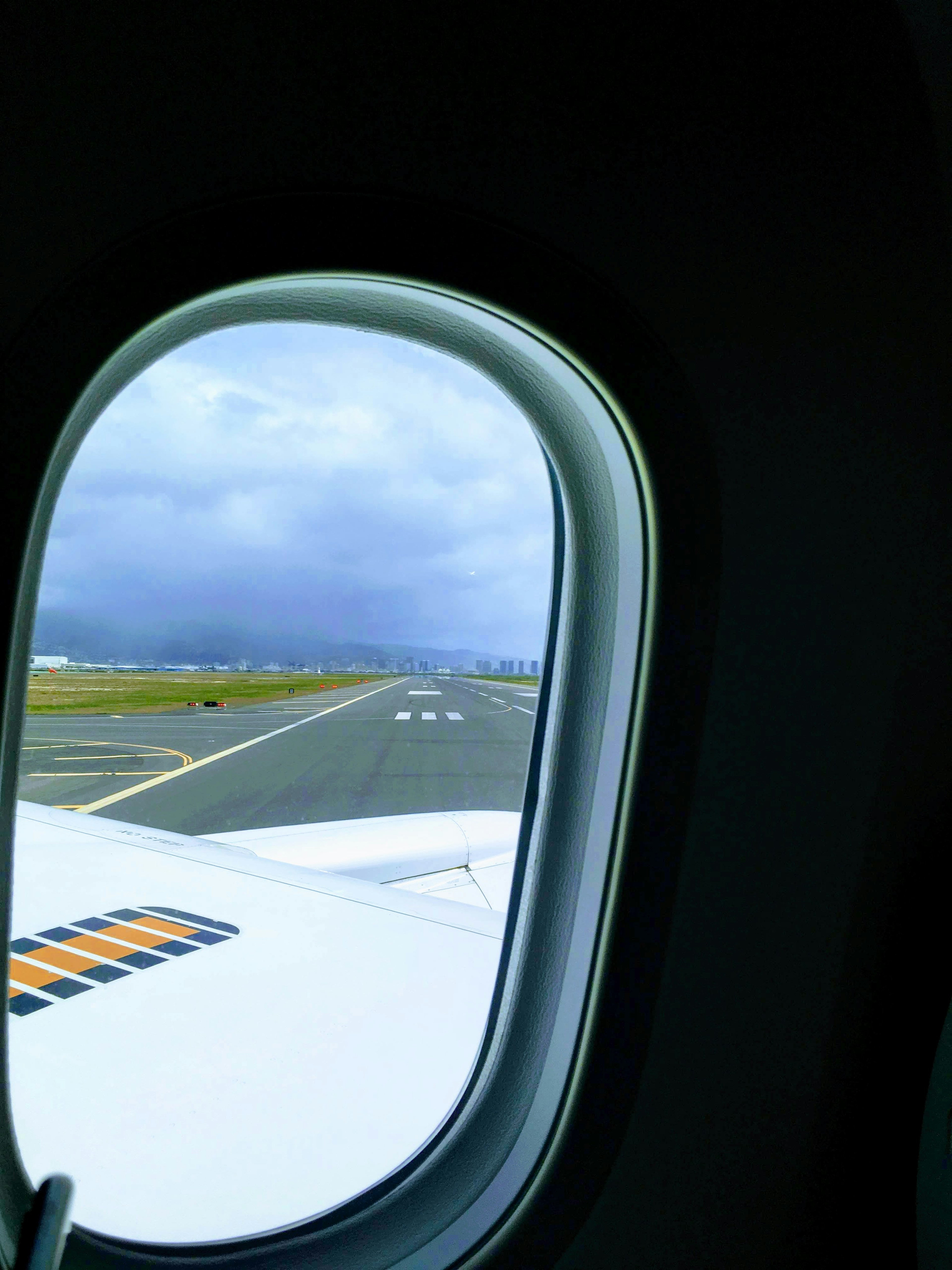 飛行機の窓から見える滑走路と雲のある空