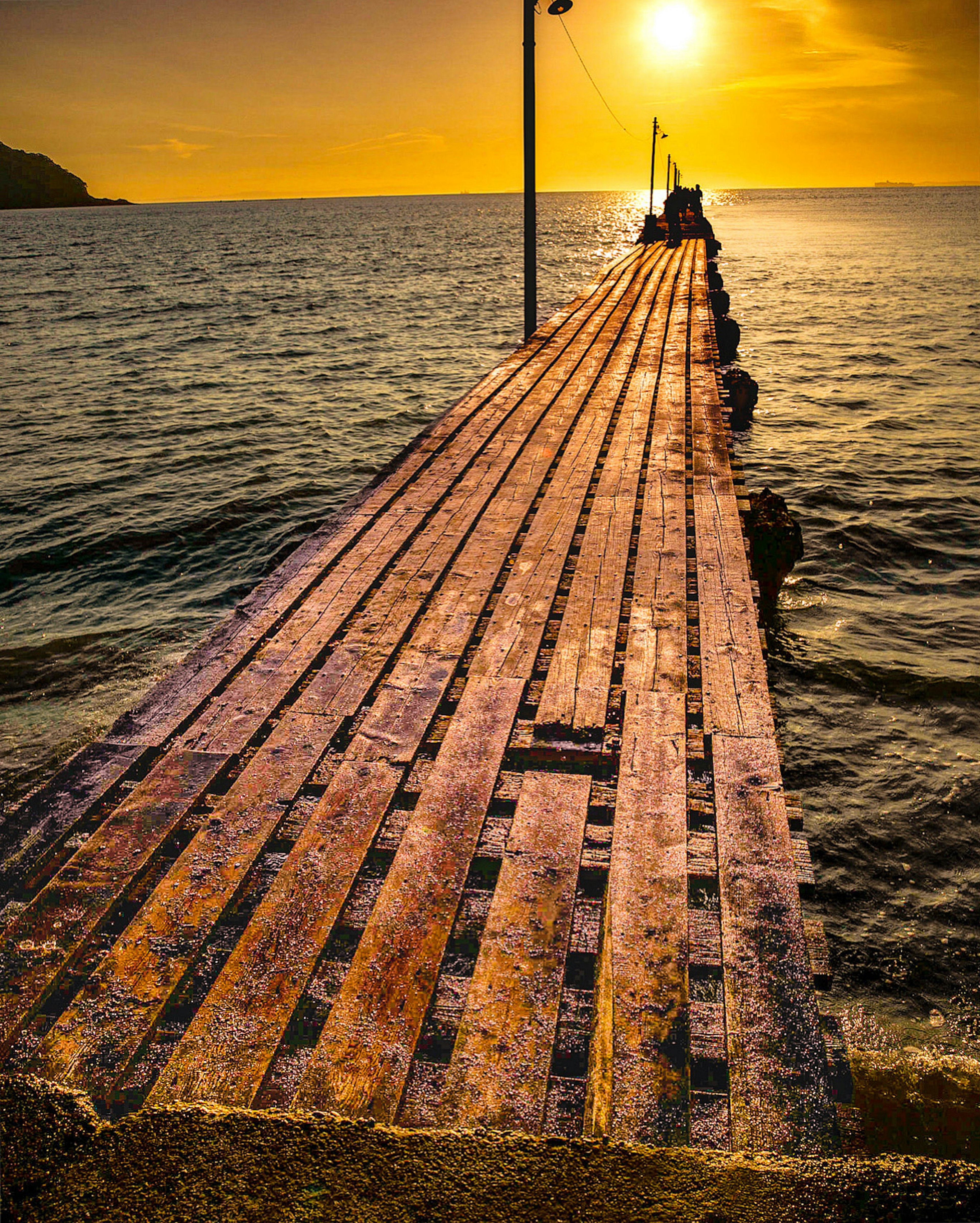 Muelle de madera que se extiende hacia el mar con fondo de atardecer