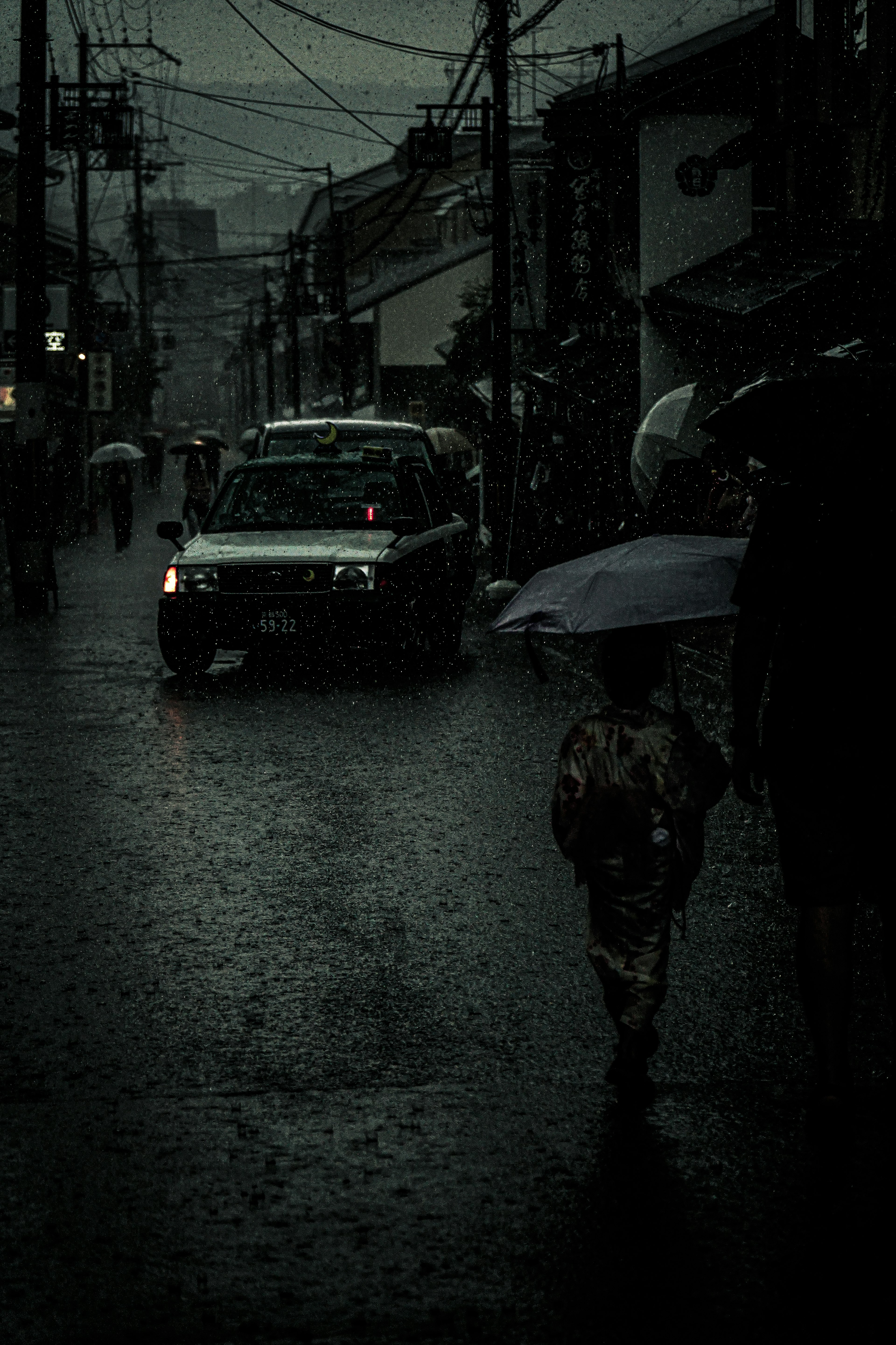 Personas caminando bajo la lluvia con un niño sosteniendo un paraguas escena de calle oscura