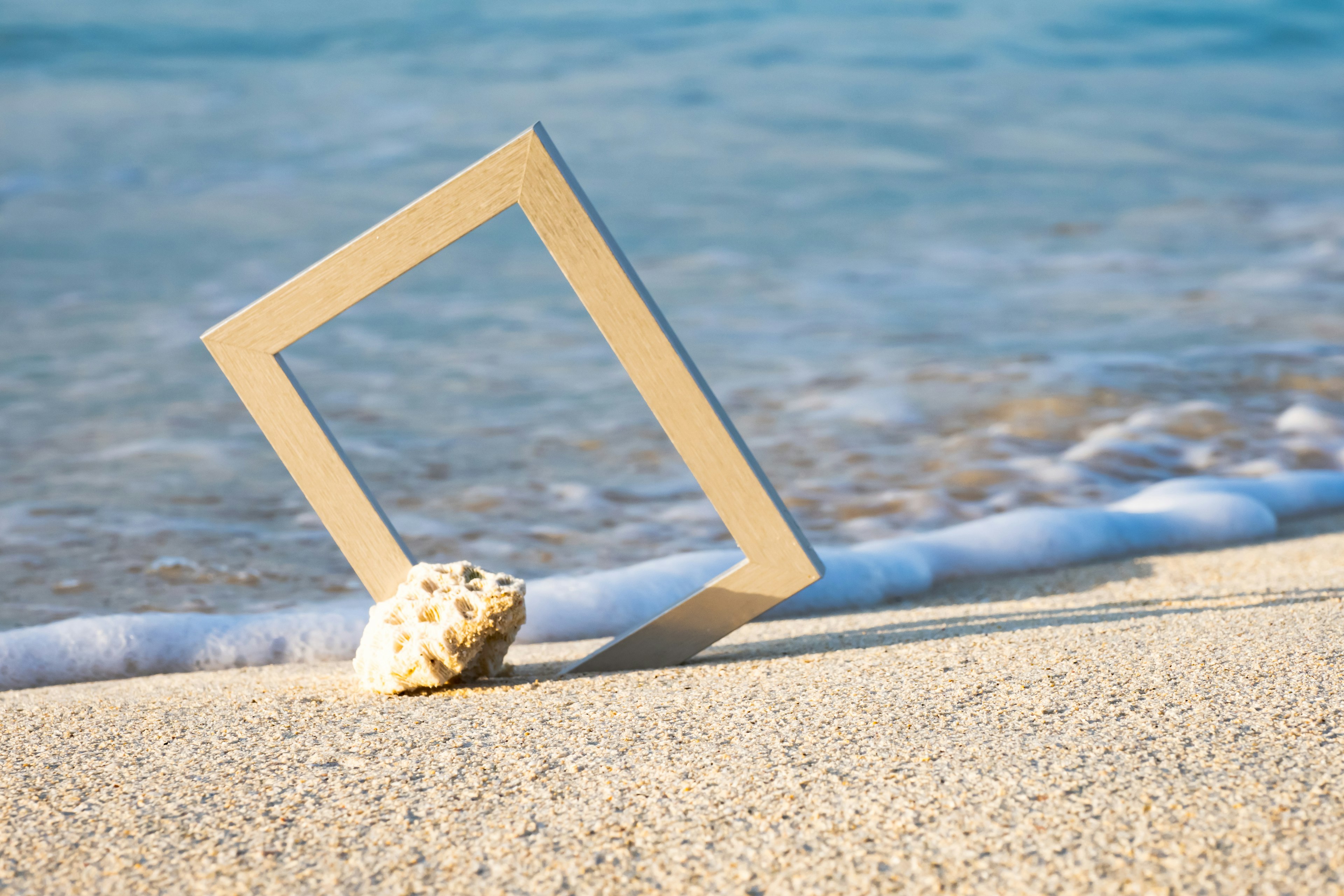 Immagine di una cornice bianca e di una conchiglia sulla spiaggia