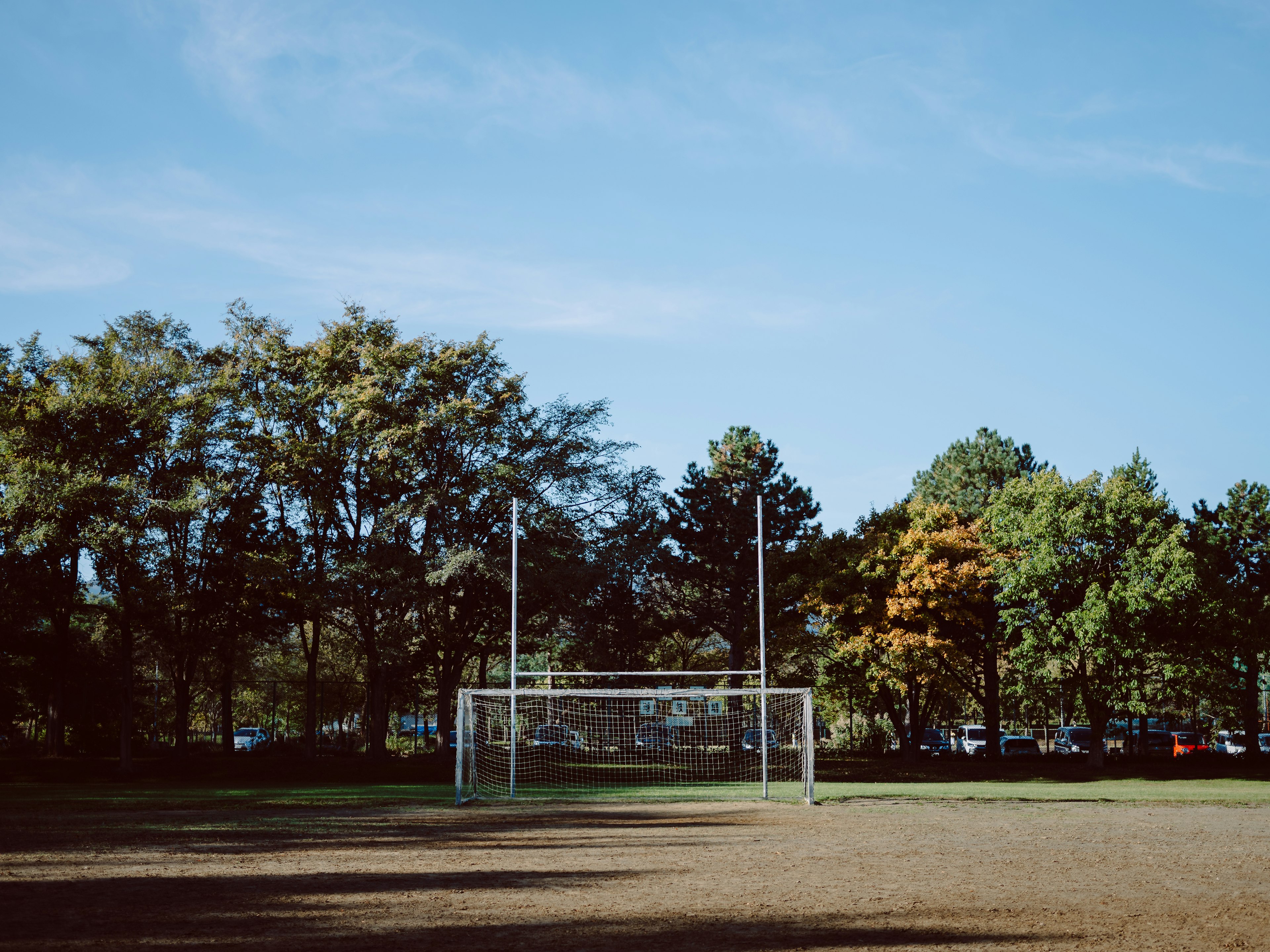 Portería de fútbol en un parque con cielo azul y árboles