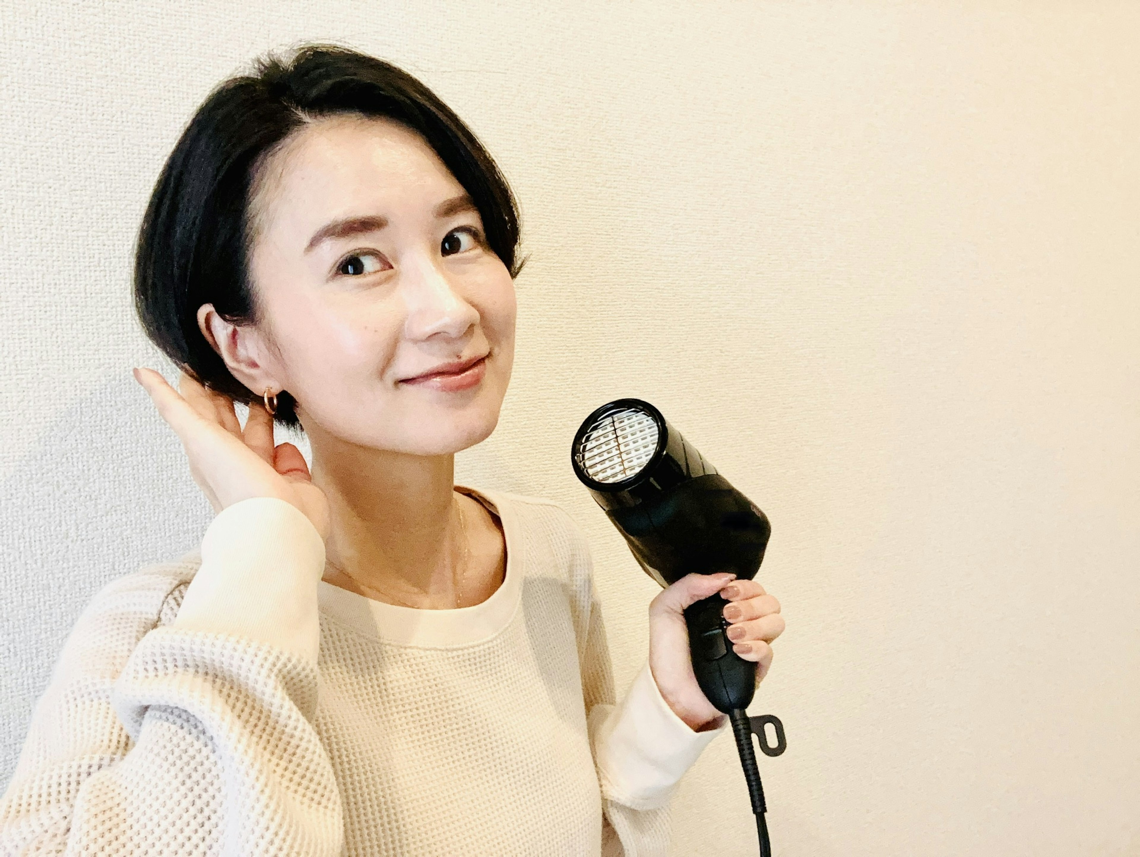 A woman smiling while holding a hair dryer