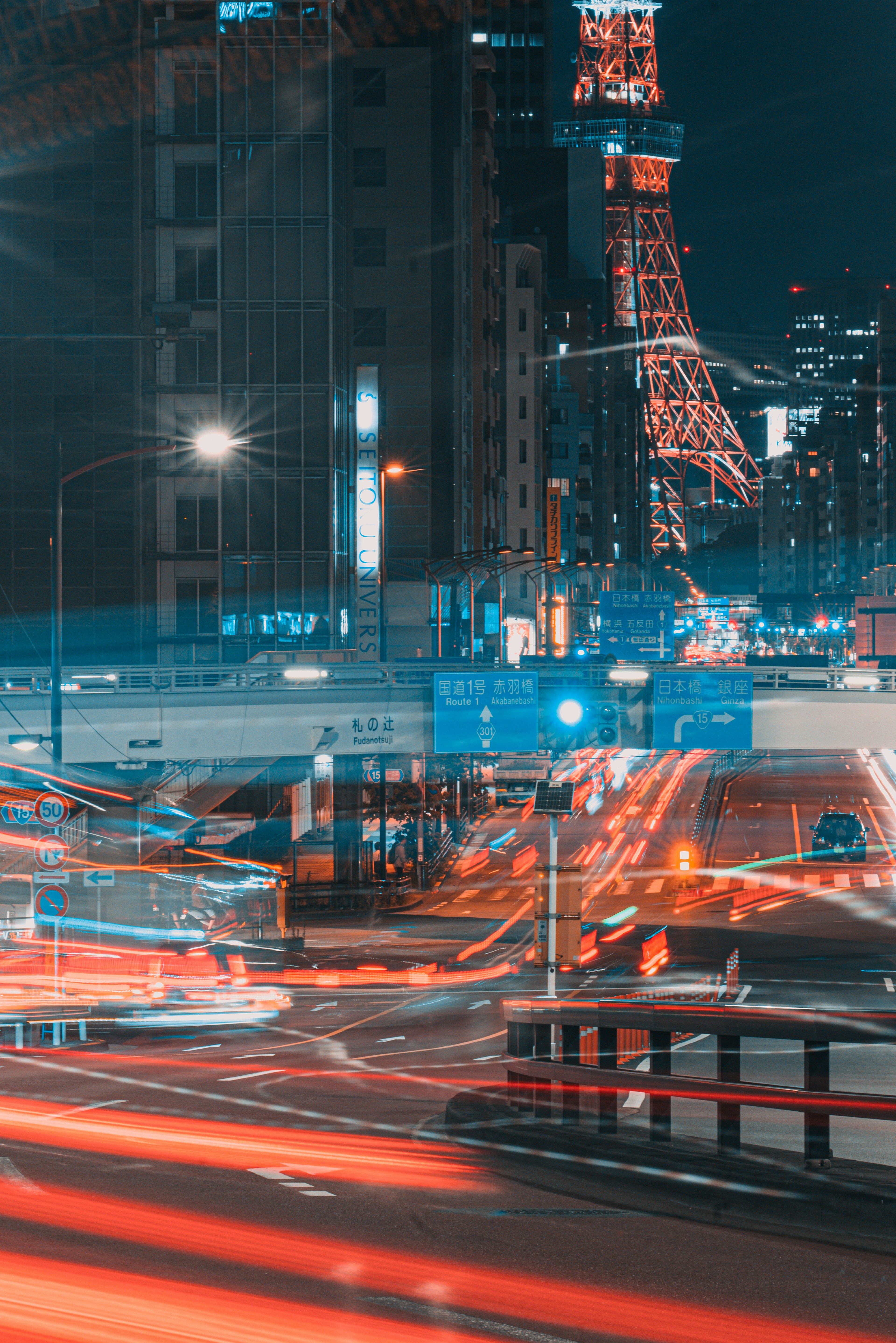 Paisaje urbano nocturno con luces de coches en movimiento y la Torre de Tokio al fondo