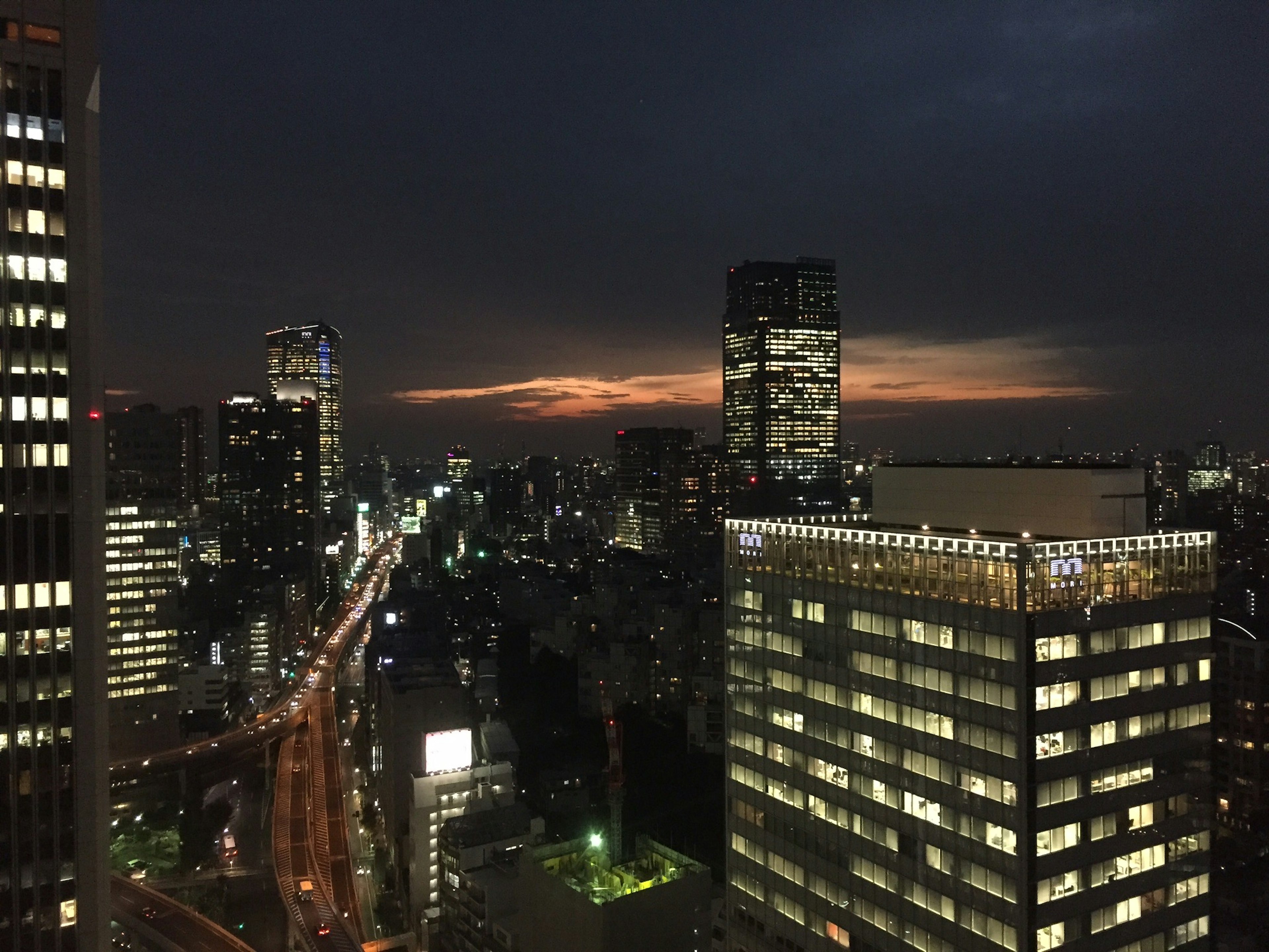 Vue nocturne de Tokyo avec des gratte-ciels et des rues illuminées sous un coucher de soleil