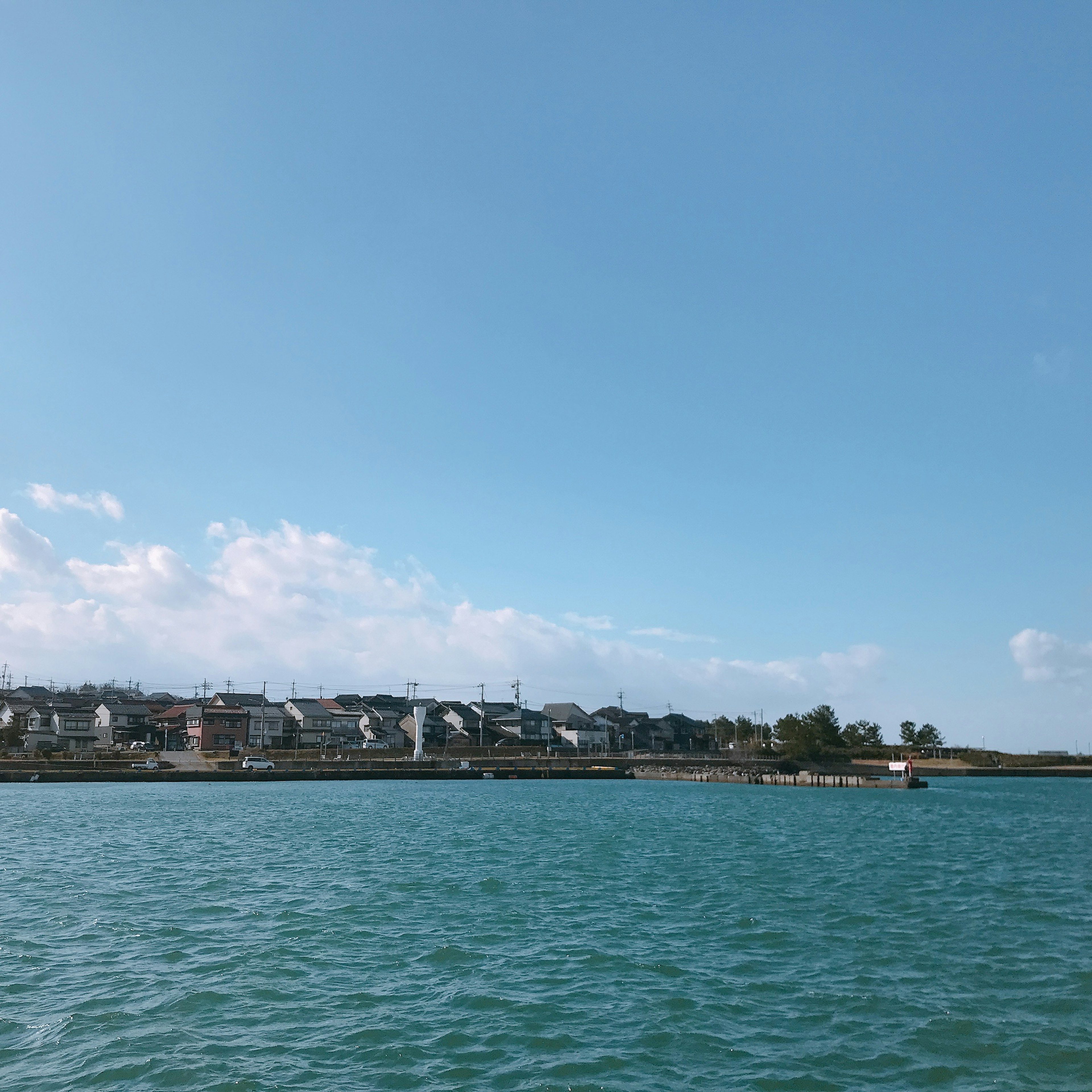 Vue côtière avec de l'eau bleue et un ciel clair avec des bâtiments résidentiels